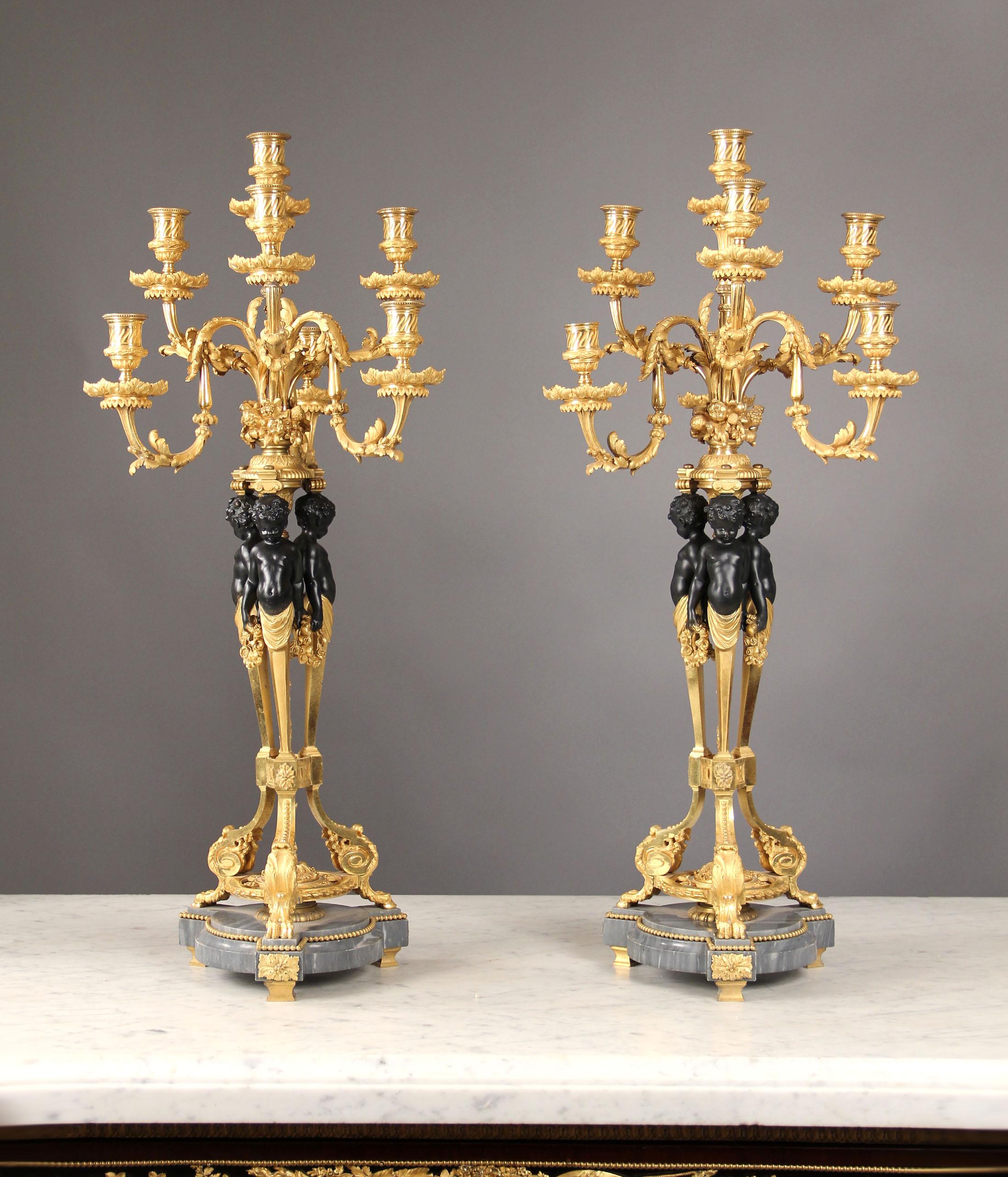 Excelente pareja de candelabros de siete luces de bronce patinado y dorado estilo Luis XV de finales del siglo XIX y principios del XX

Cada uno con base de trípode calado con pies de pezuña, el estandarte con tres bustos de querubines que sostienen