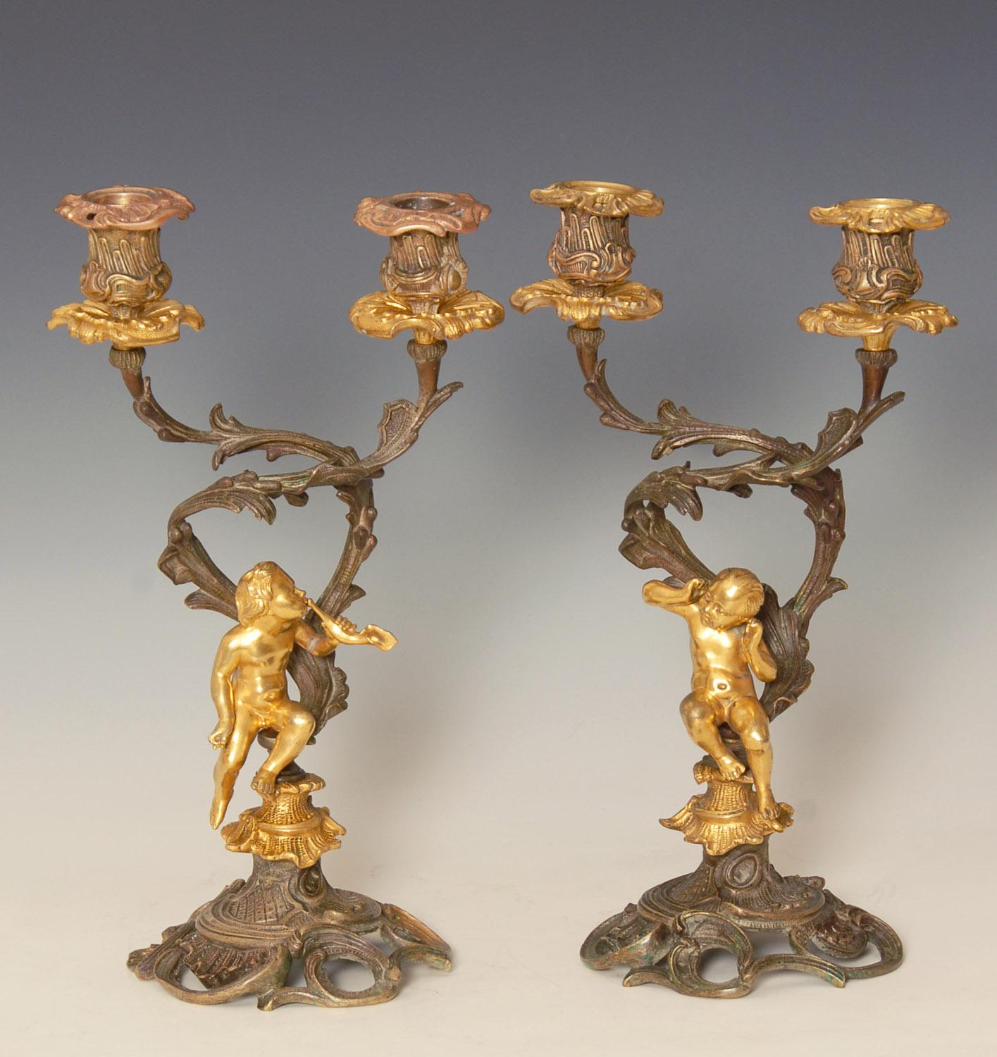Absolutely charming pair of late 19th century Putti / Cherub candelabra, probably French.
gilt figures on patinated bronze.
The male figure is blowing a horn type instrument while the other is cocking her ears to listen.

Heavy solid pieces