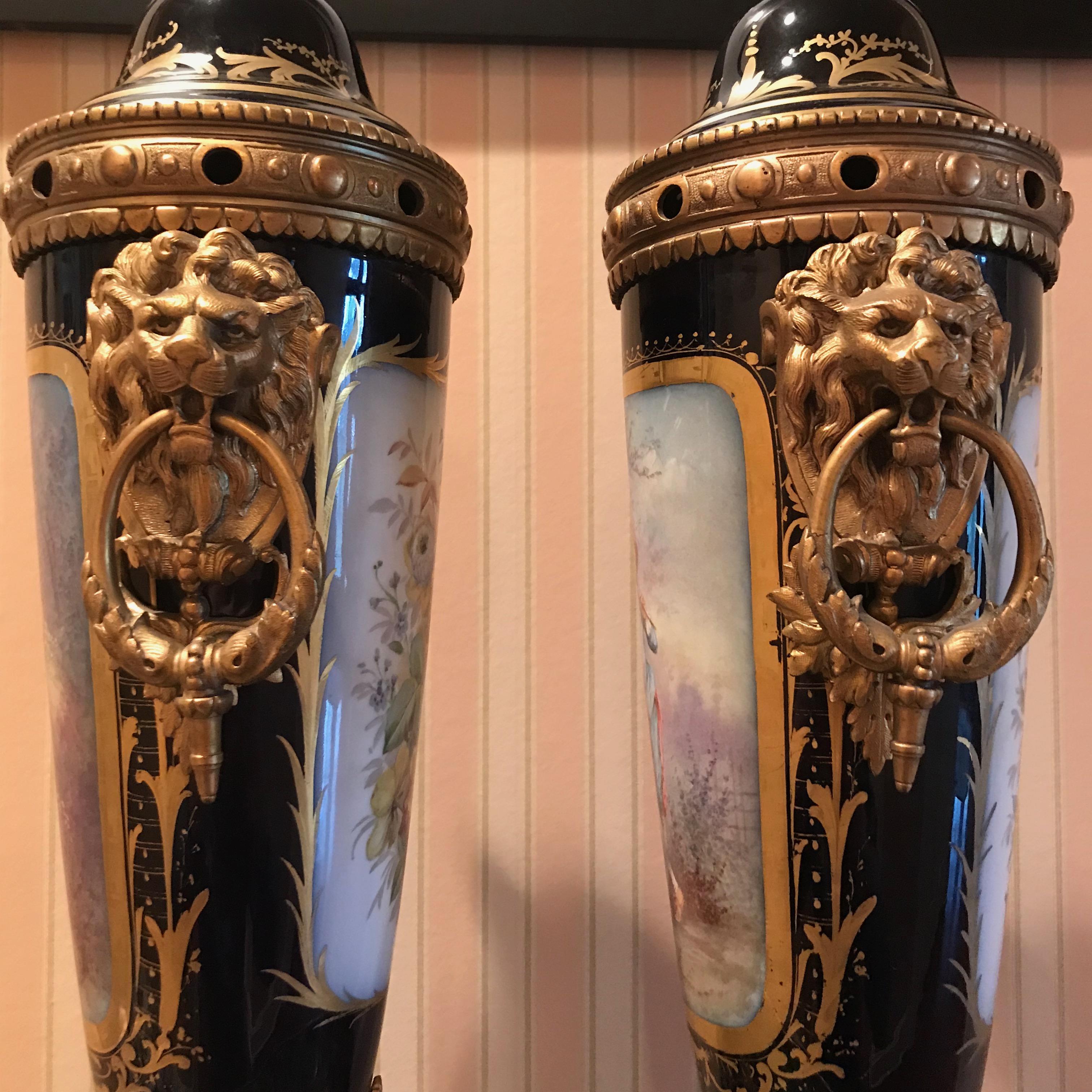 A pair of late 19th century Sèvres Porcelain lidded garniture vases with gilt bronze mounts. The tall tapered bodies decorated with hand painted scenic panels depicting a lady and gentleman wearing 18th century style costume in romantic garden