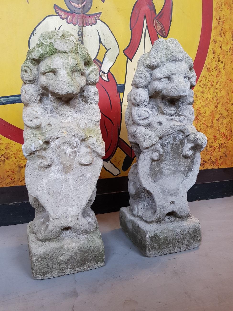 Set of two late 19th century stone garden lions holding a shield (both have traces of erosion).

The measurements are,
Depth 19 cm/ 7.4 inch.
Width 19 cm/ 7.4 inch.
Height 57 cm/ 22.4 inch.