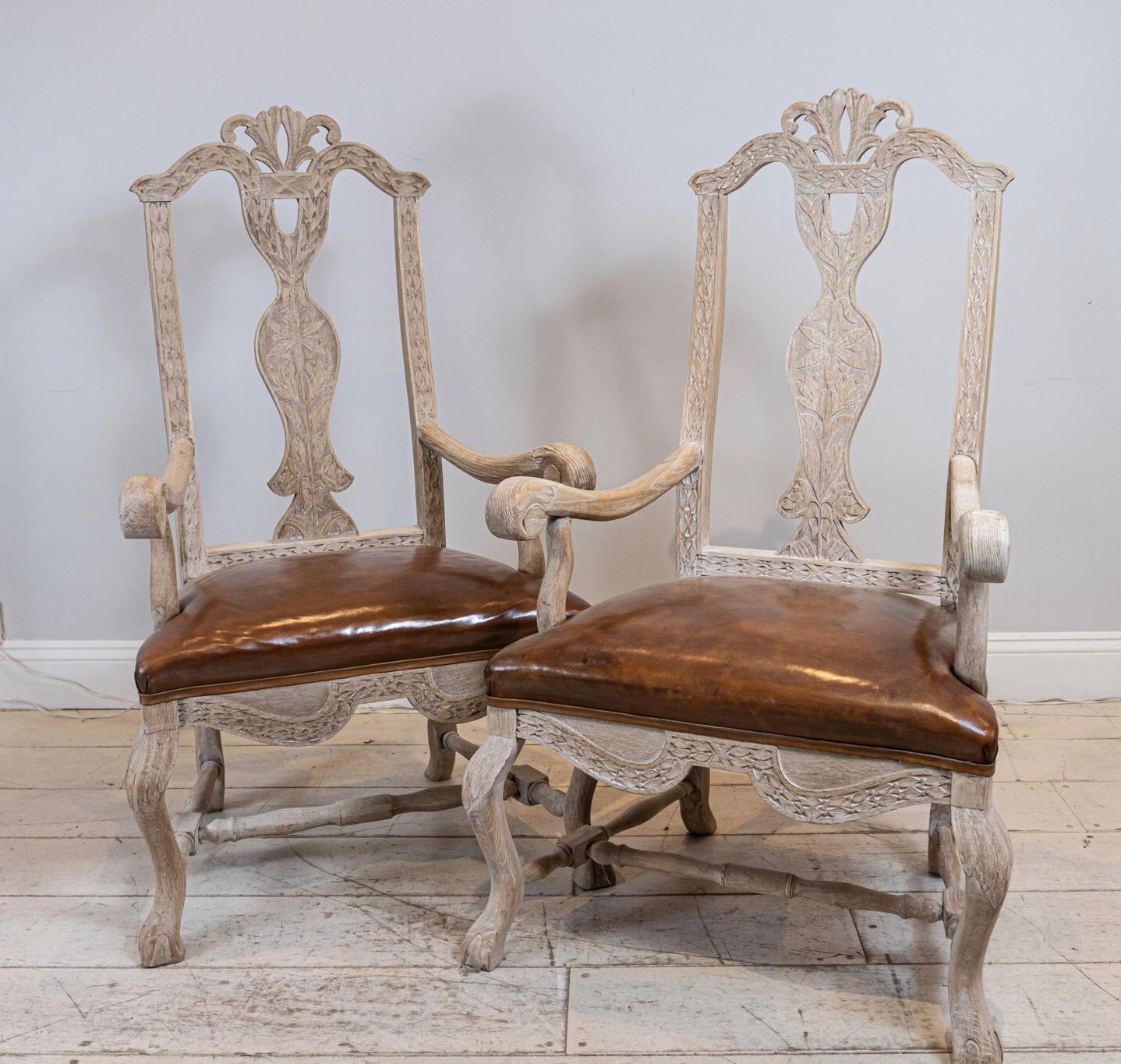 A pair of multifunctional bleached Oak Swedish carvers or side chairs. Featuring scrolled arms, decoratively carved seat backs and front frieze. The chairs have been reupholstered in a warm mid-tan leather.

Perfect as dining table or handsome