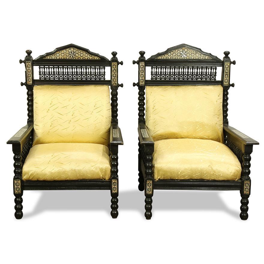Pair of Late 19th Century Syrian ebonized wood and mother-of-pearl inlaid chairs, each with back having spindle turned reticulated panels, above a golden upholstered seat and back, and rising on turned legs, 