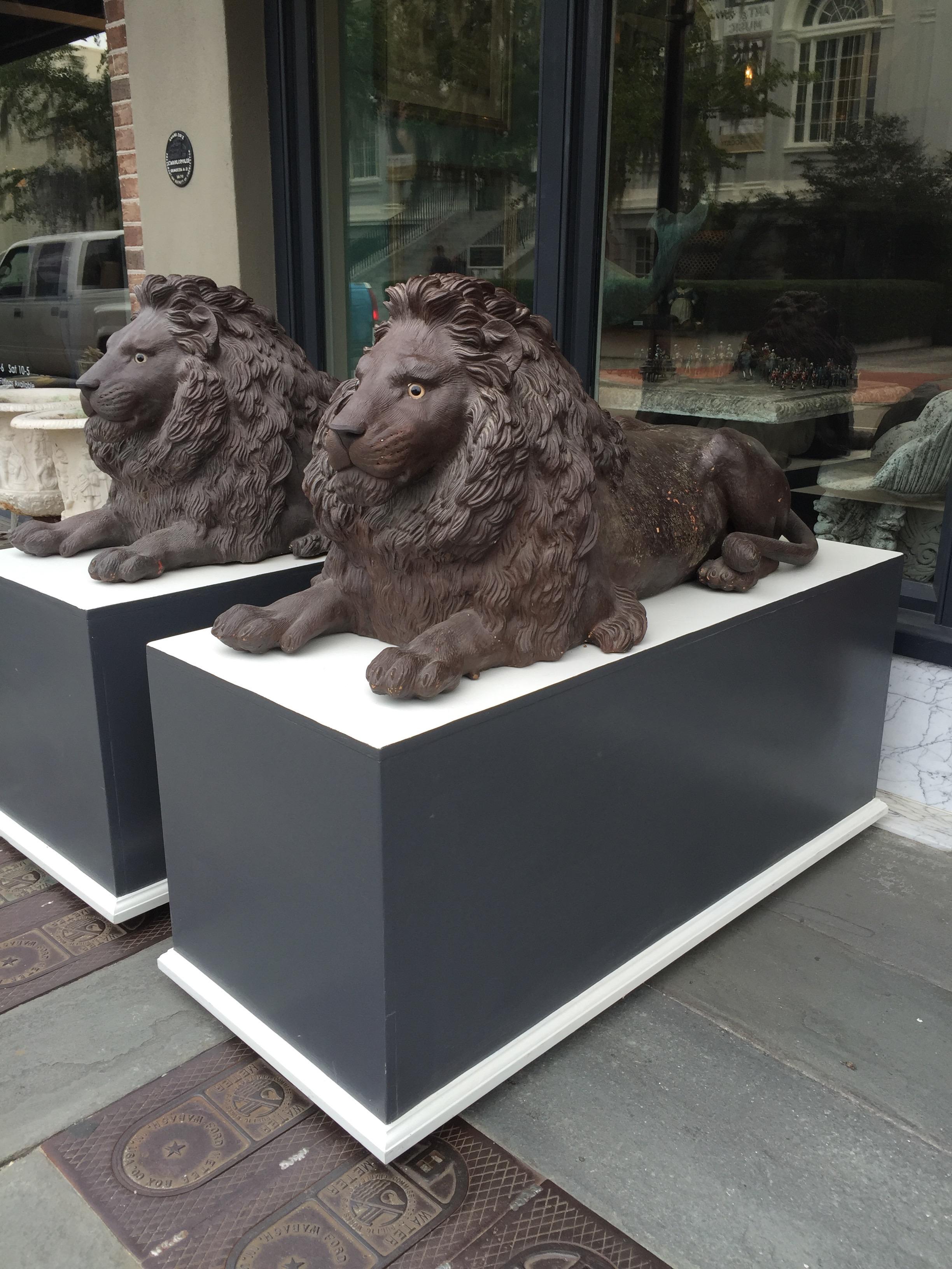Pair of late 19th century terracotta lions in resting pose. Originally had full sets of whiskers that are mostly gone but remnants still remain. Glass eyes and vigilant faces provide a very imposing but charming look.  