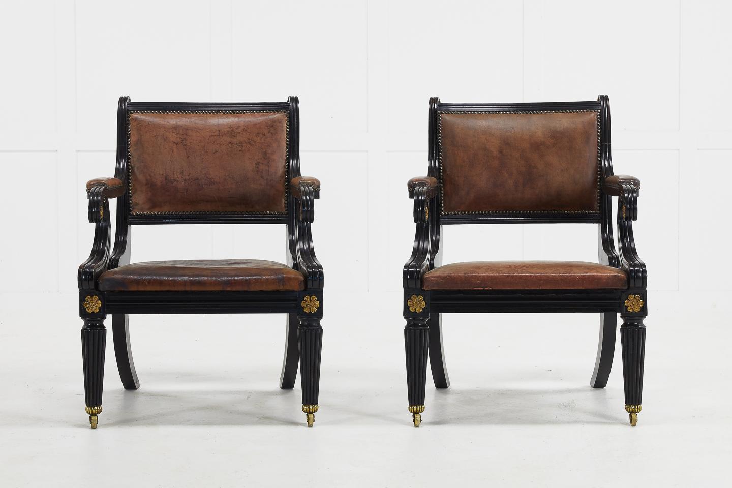 Pair of shapely, late 20th century English Regency style ebonized armchairs with gilt metal decoration. Upholstered in tan leather.