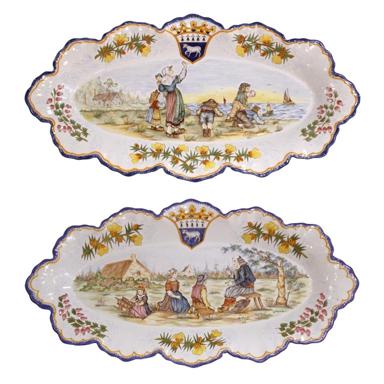 Un encantador par de fuentes de pared de loza pintadas a mano de la afamada alfarería Henriot Quimper de Bretaña, Francia. Cada fuente alargada de borde festoneado está ricamente decorada con una colorida escena pastoral en la que aparecen figuras