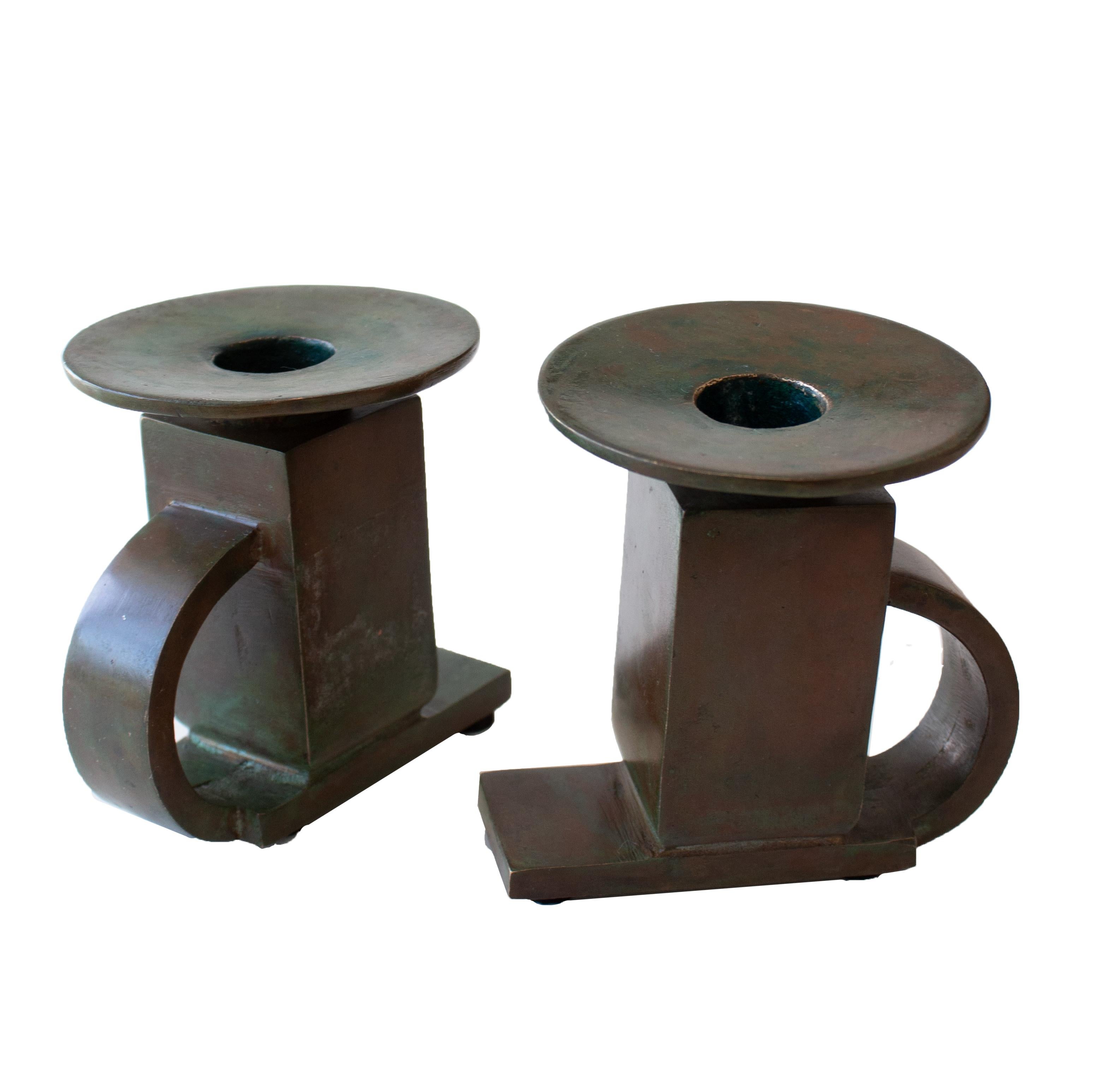 A pair of patinated bronze candlesticks designed by Swedish artist Sune Bäckström around 1940 (model 9040). Sculptural late Functionalist design with a distinctly architectural – almost brutalist – character, featuring an arched back/handle and