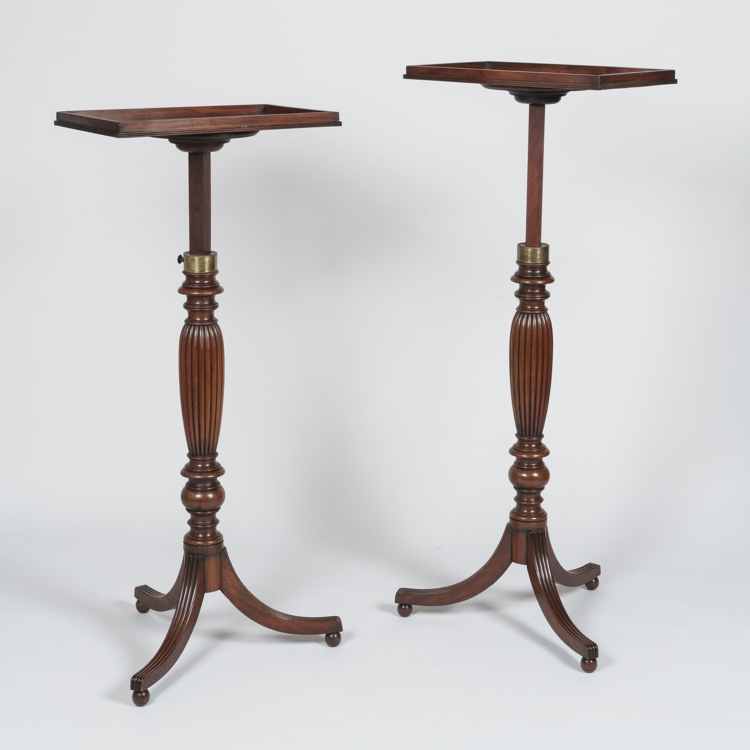 A Pair of Late Georgian adjustable tripod tables
Attributed to Gillows

Carved from mahogany, the tables supported on fluted and splayed legs with carved ball feet, the turned and reeded baluster-shaped stems of adjustable height having