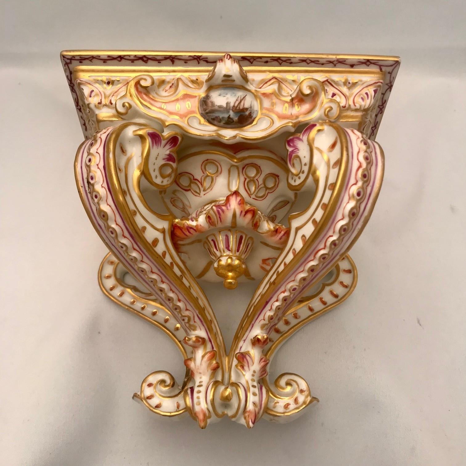 This antique pair are painted and gilt with stylized acanthus and raised ornament. Each also is painted in a small oval reserve with a ship in harbour. They are marked with the crossed swords and star.
