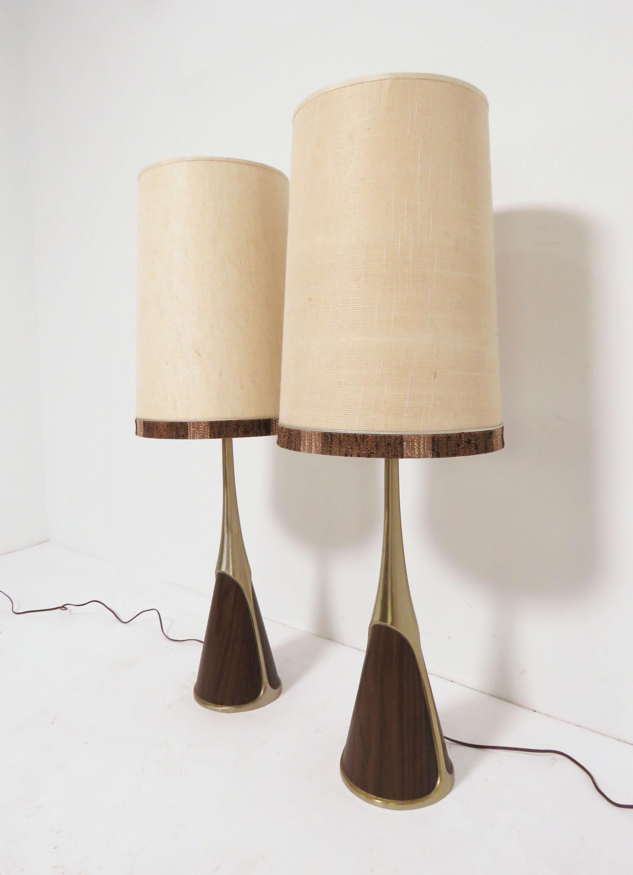 A pair of all original cast metal lamps with panels of teak veneer, circa 1960s by the Laurel Lamp Company. Original period linen shades with hand weave banding are included with these lamps. 

With shades, these measure 40.5