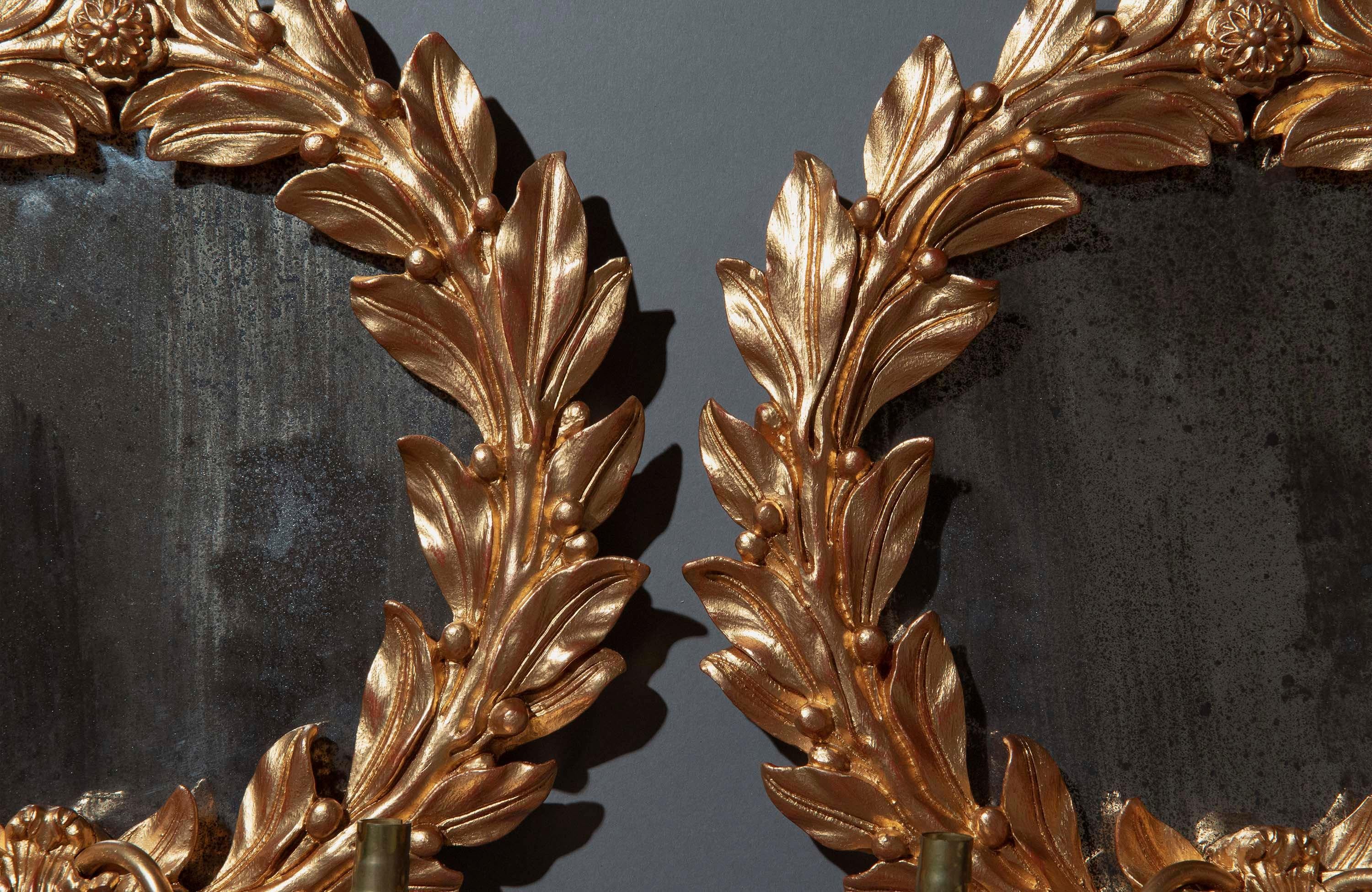 A stylish pair of laurel wreath shaped wall lights, with antiqued mirror plates and twin-arm sconces.
Mid-20th century.

Why we like them
Very chic objects for classic or eclectic interiors.

Ancient Greeks and Romans greatly valued the noble laurel