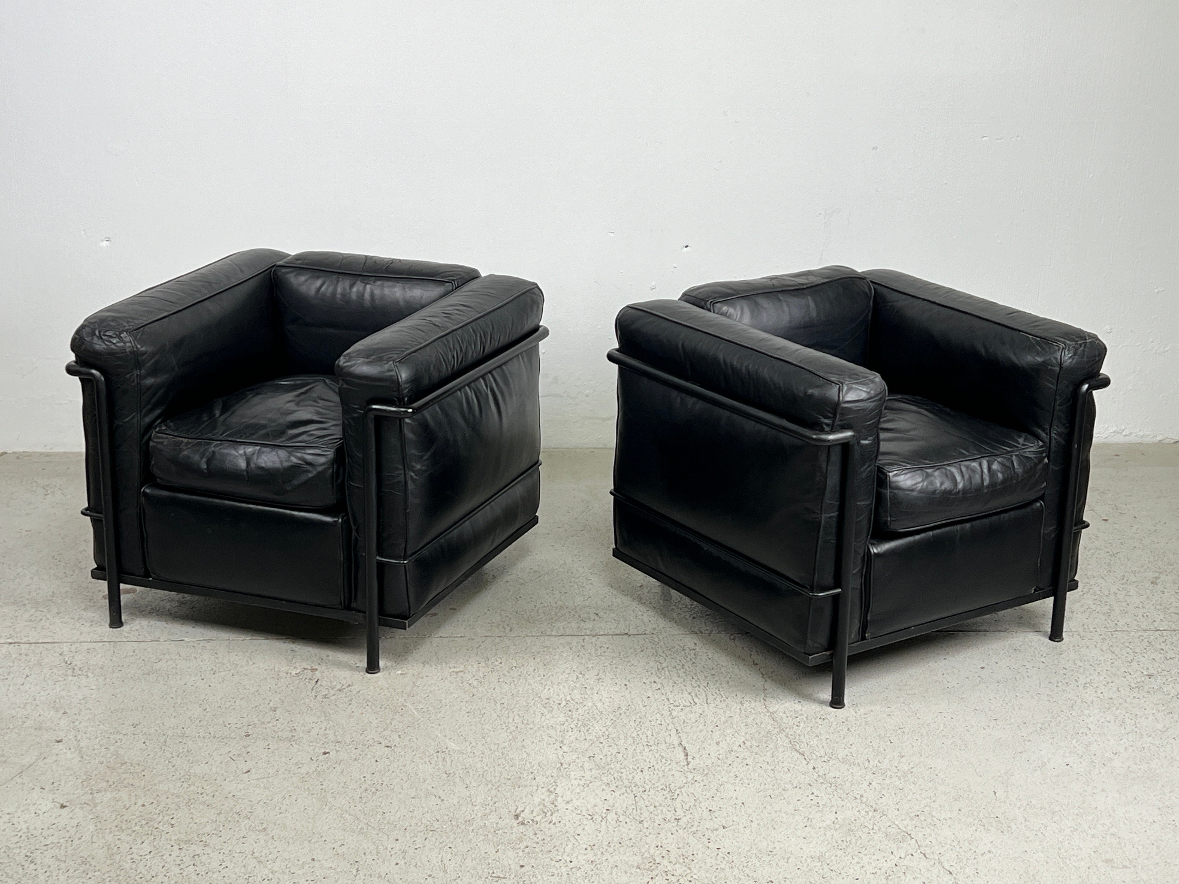 Une paire de fauteuils club LC2 petit confort avec des cadres noirs d'origine et un cuir noir magnifiquement patiné. Conçu par Le Corbusier et produit par Cassina. 