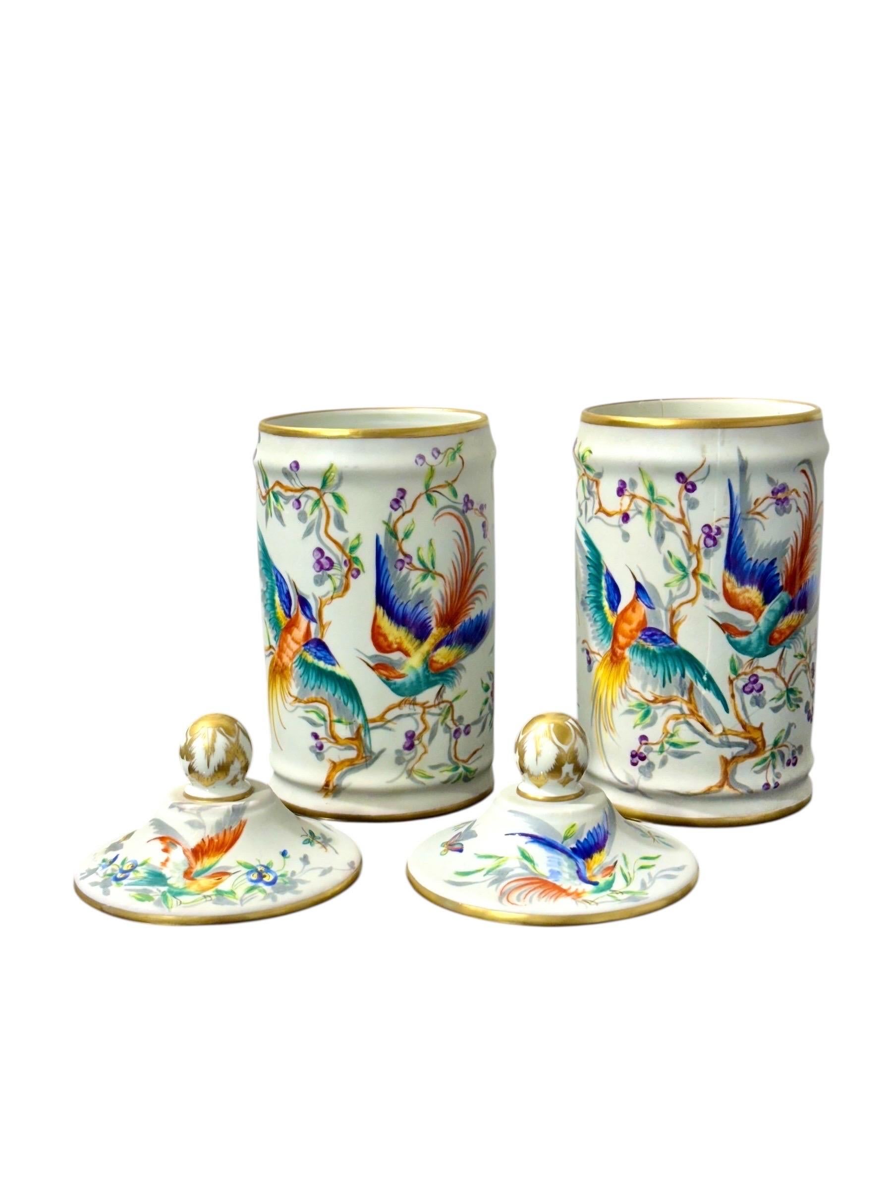 This beautiful pair of Paris porcelain apothecary jars was entirely hand-painted in the celebrated Le Tallec workshop, active in Paris during the mid-20th century. Each jar features richly detailed scenes of exotic birds perched among flowering