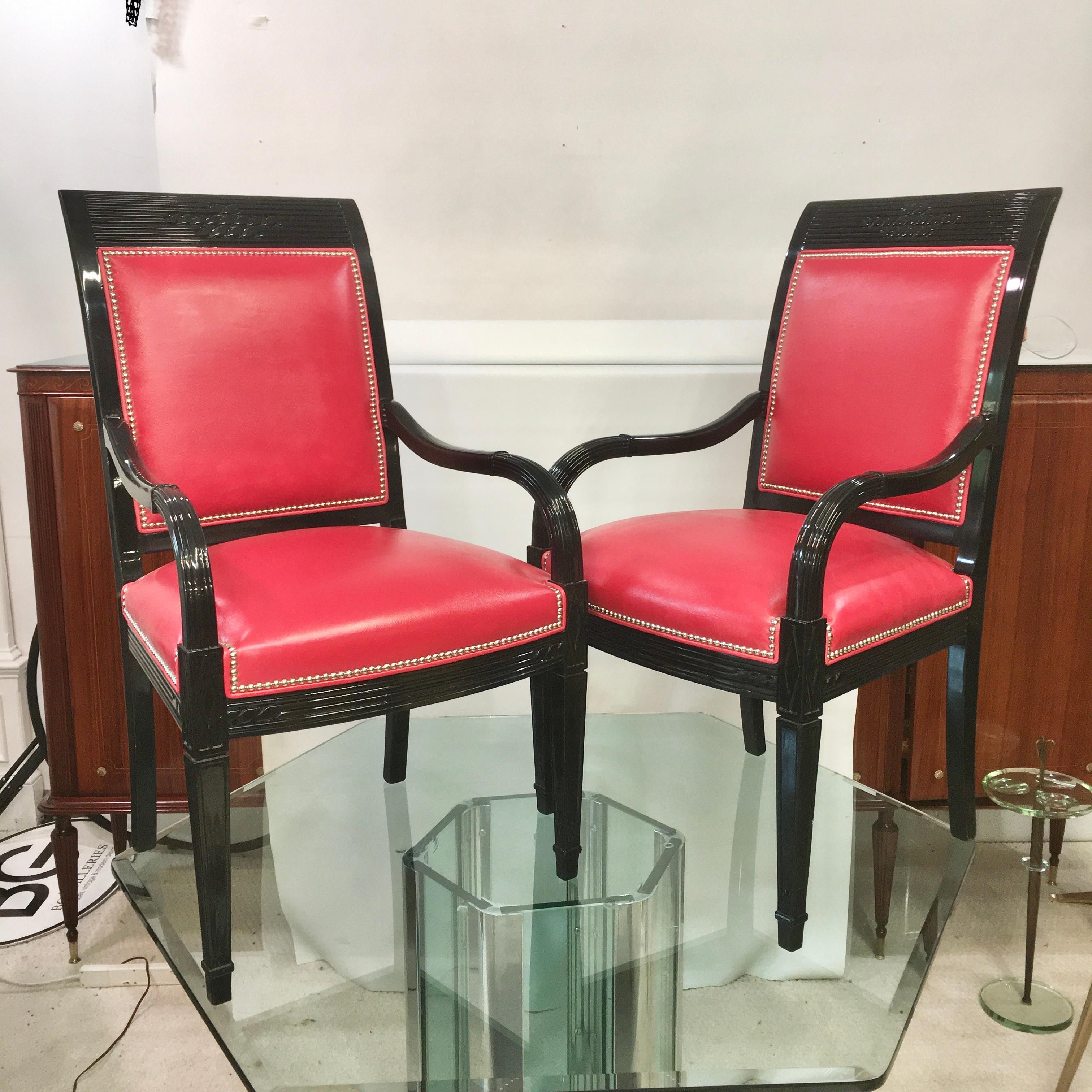 Pair of Art Deco style black lacquered armchairs with red leather upholstery and nickel plated brass nailheads. 
Arm height 25 inches.
 