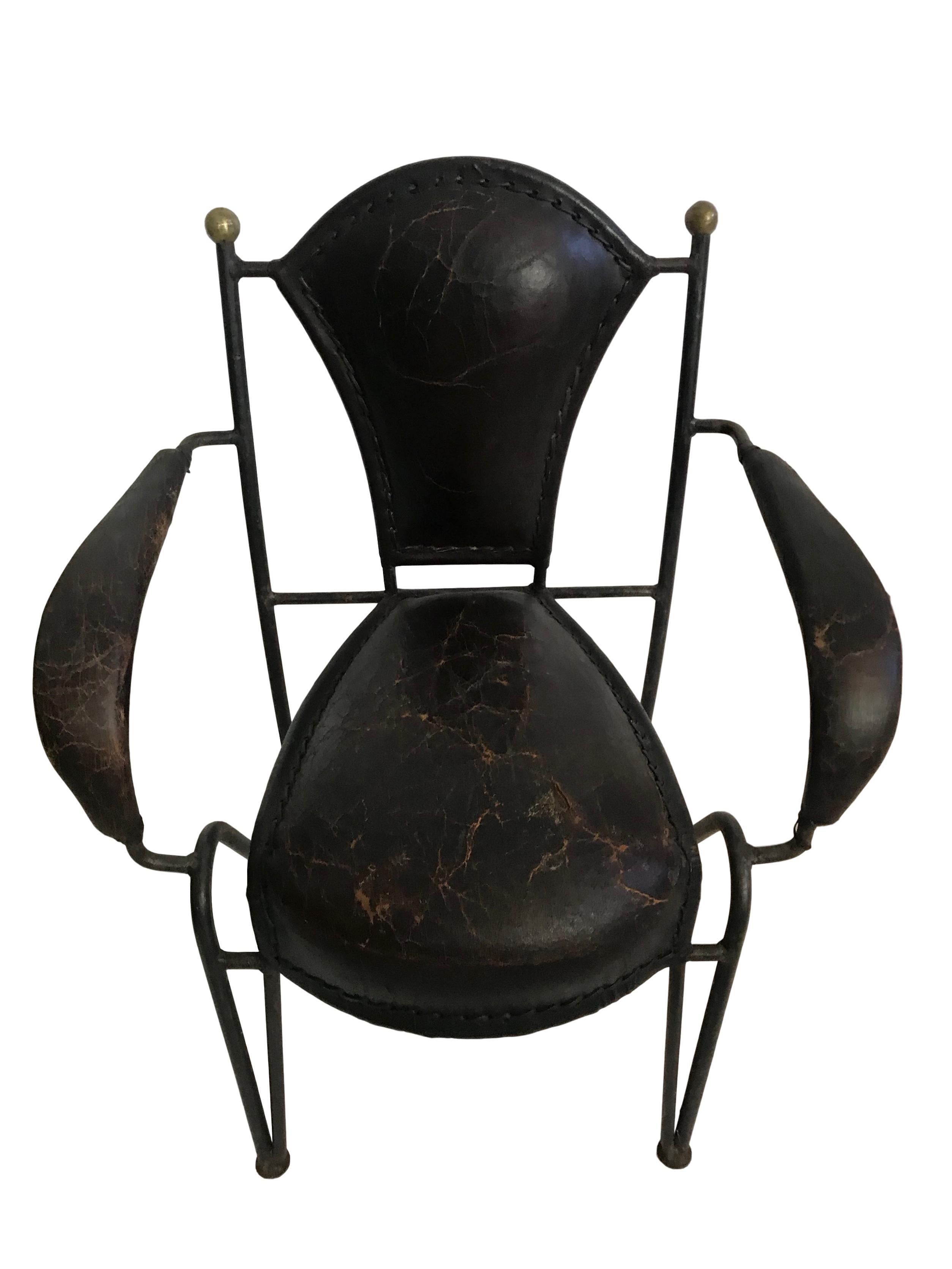 This is a unique pair of children's arm chairs with iron frame and leather seat and armrests. On the top of the backrest are gold overpainted knobs which add great character.