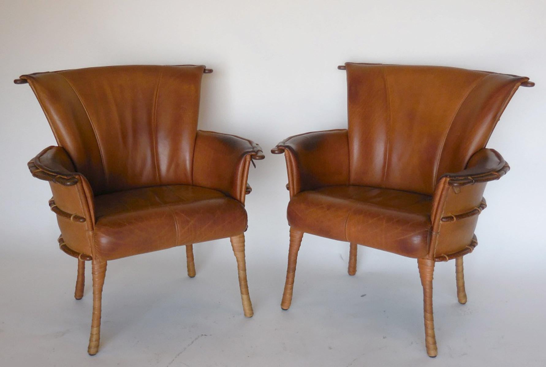 This pair of club chairs were made in Australia, in the 1990s. Constructed of palm wood and leather. Unusual tapered leather wrapped legs. The back of the chair is decoratively supported by ribs of sustainable palm wood. The front and back of each
