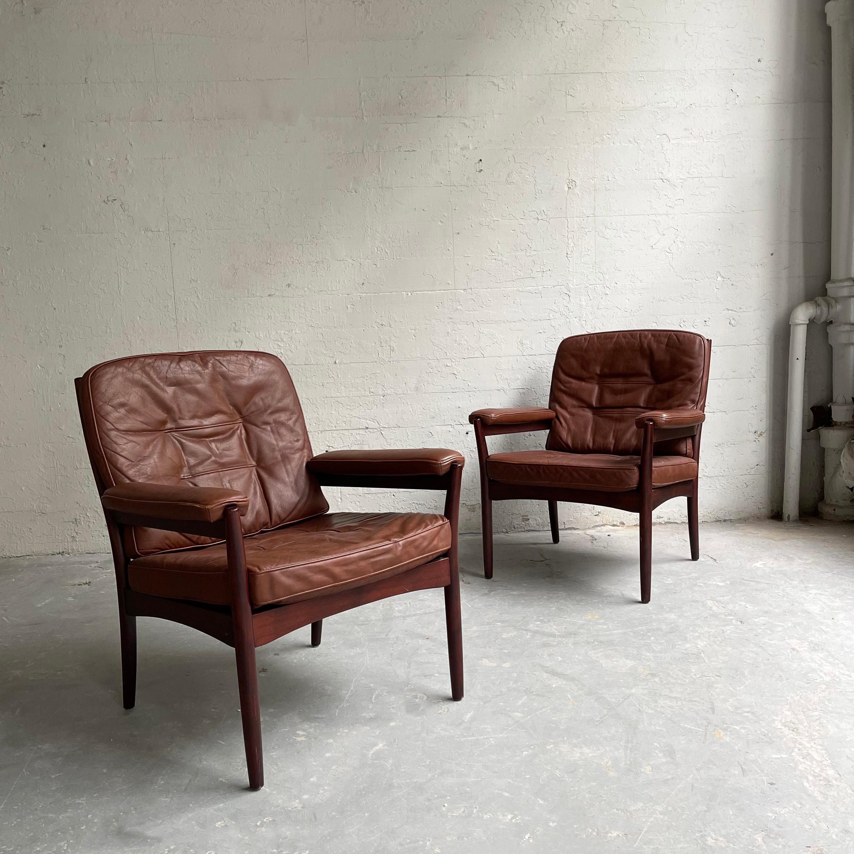 Pair of Scandinavian Modern armchairs by Göte Möbel Sweden, feature rosewood frames with patinated, cognac leather upholstery.