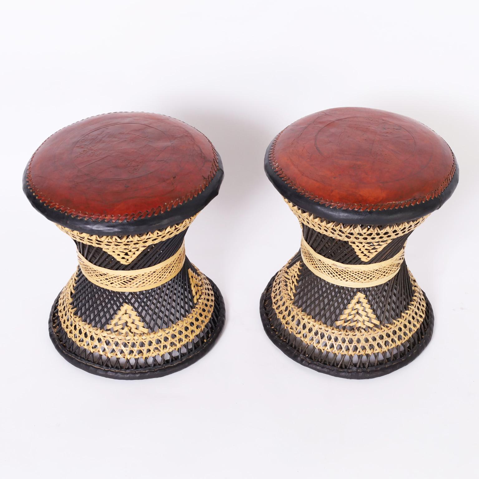 Impressive pair of mid century Anglo Indian stools or seats with leather tops featuring embossed images of the Taj Mahal on classic hourglass form wicker bases paint decorated in black.
