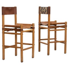 Pair of leather and wood sling stools by Abel Gonzalez