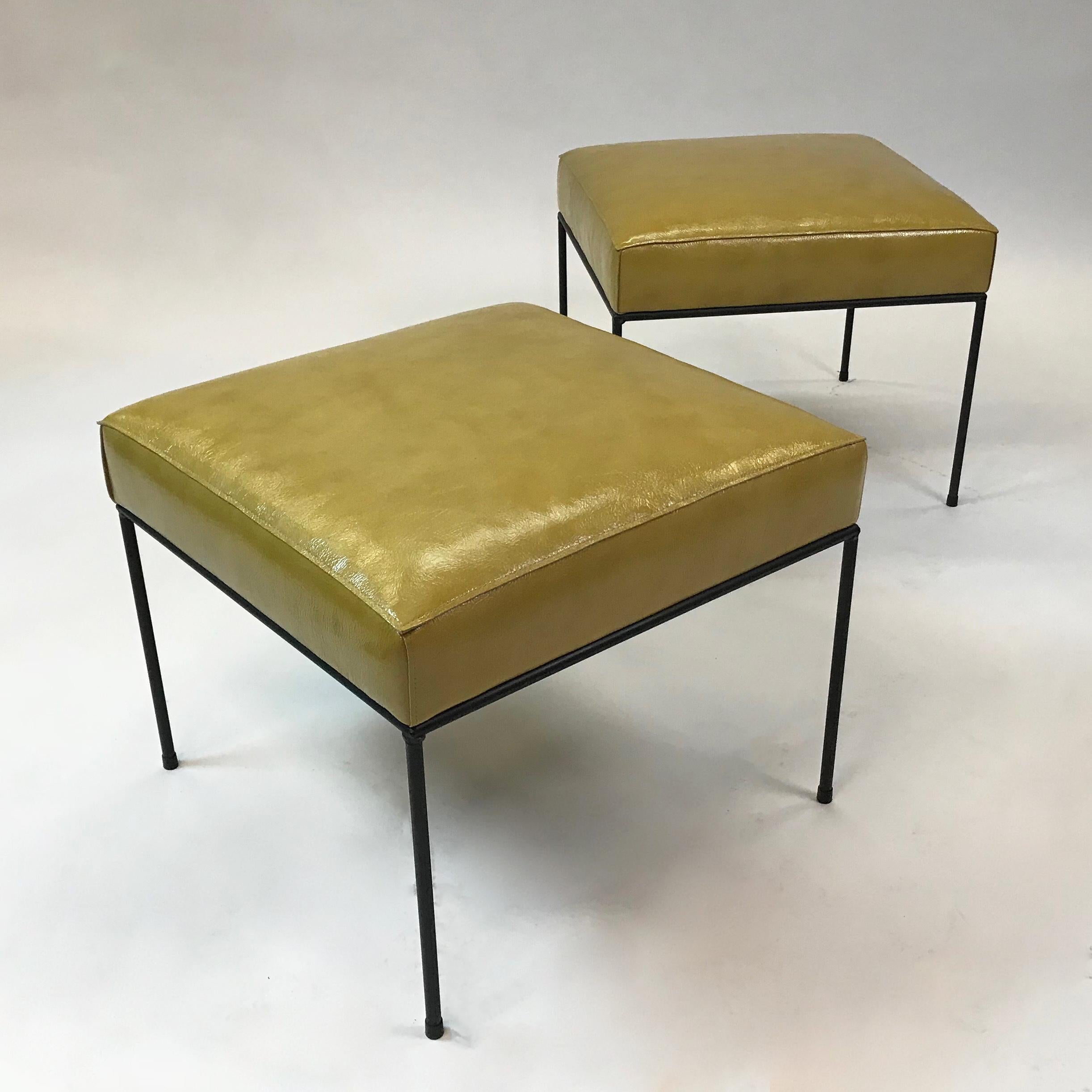 Pair of Mid-Century Modern, low-profile, square ottomans, stools or benches by Paul McCobb feature minimal, black wrought iron frames and are newly upholstered in mustard green, textured leather with live edge upholstery as shown. Listed price is