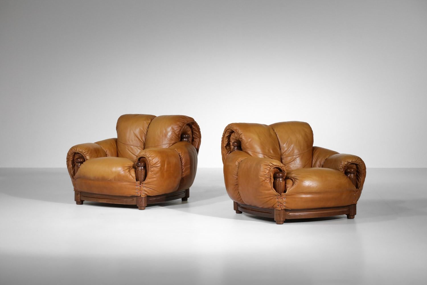 Coppia di poltrone italiane vintage degli anni '70. Struttura in legno massiccio, sedute e schienali in pelle cognac. Forma e design piuttosto originali con un bel dettaglio di intrecci negli angoli delle sedie. Il set è in ottime condizioni vintage