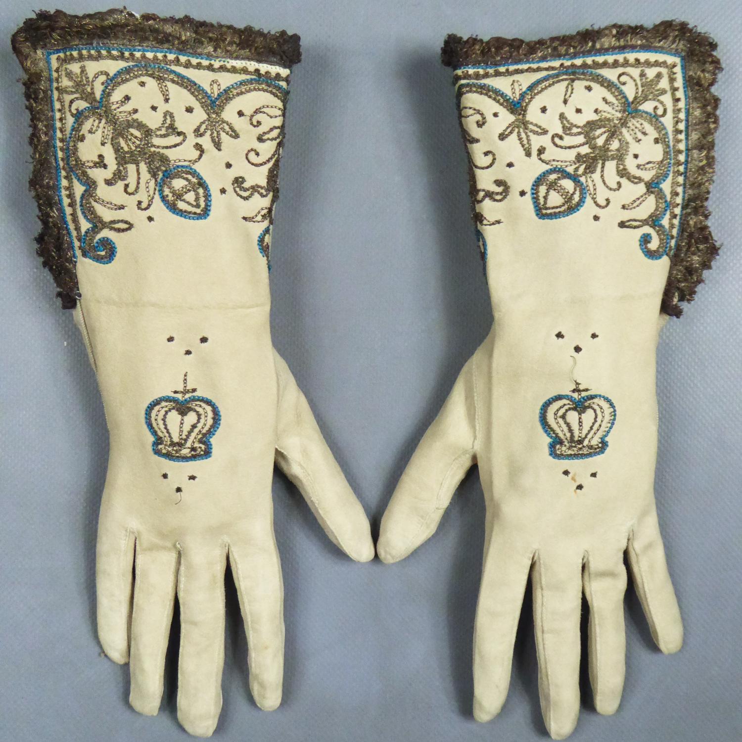 Late 19th century
England

Astonishing pair of bishop's gloves with the British crown dating from the end of the 19th century. In 17th century style, this pair of cream suede gloves embroidered in chain stitch with golden and silver metallic