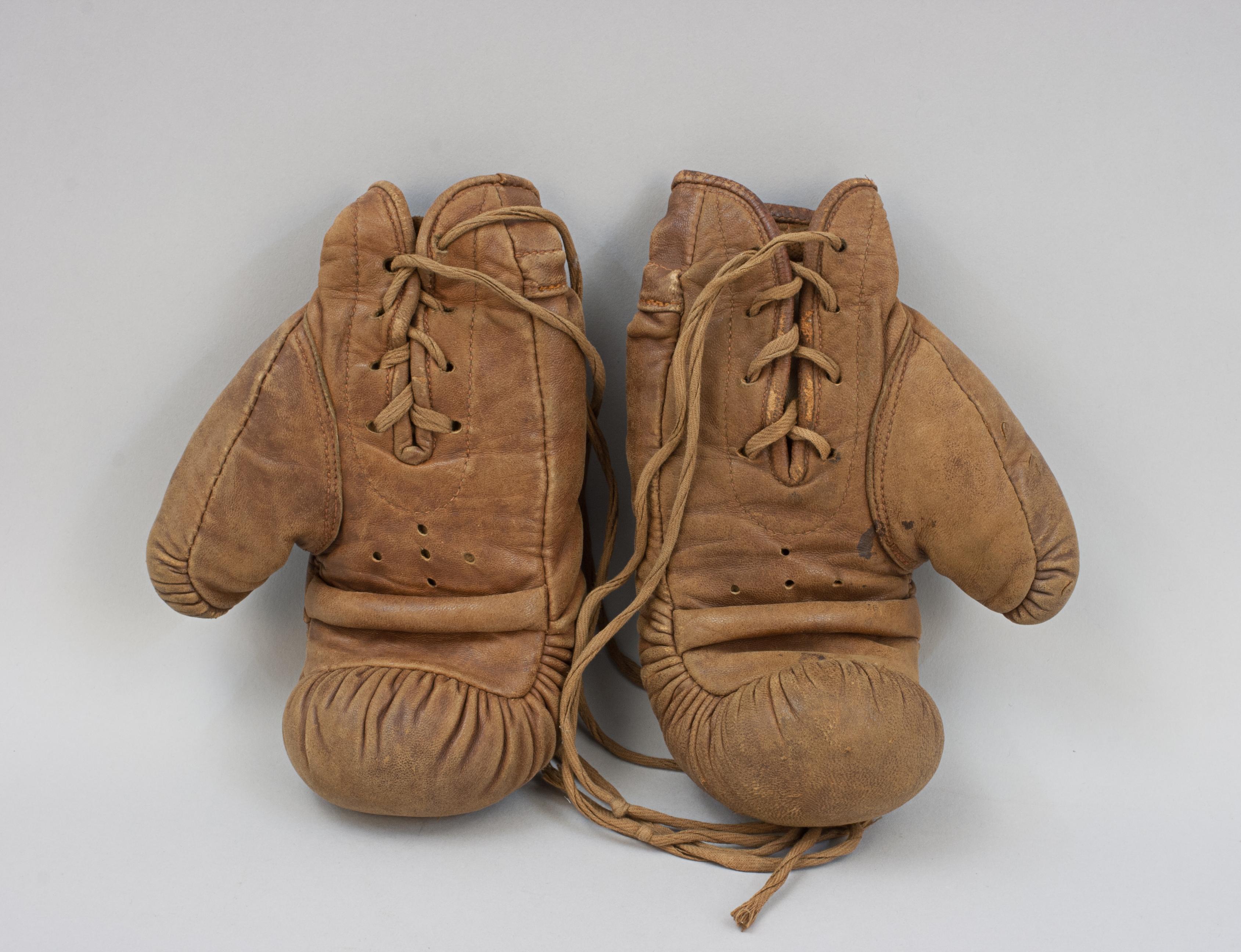 Gants de boxe en cuir vintage pour enfant.
Une paire de gants de boxe en cuir fauve fabriquée par Frank Bryan, un fabricant connu d'équipements sportifs au début et au milieu du 20e siècle. Ces gants, dont les articulations sont généreusement