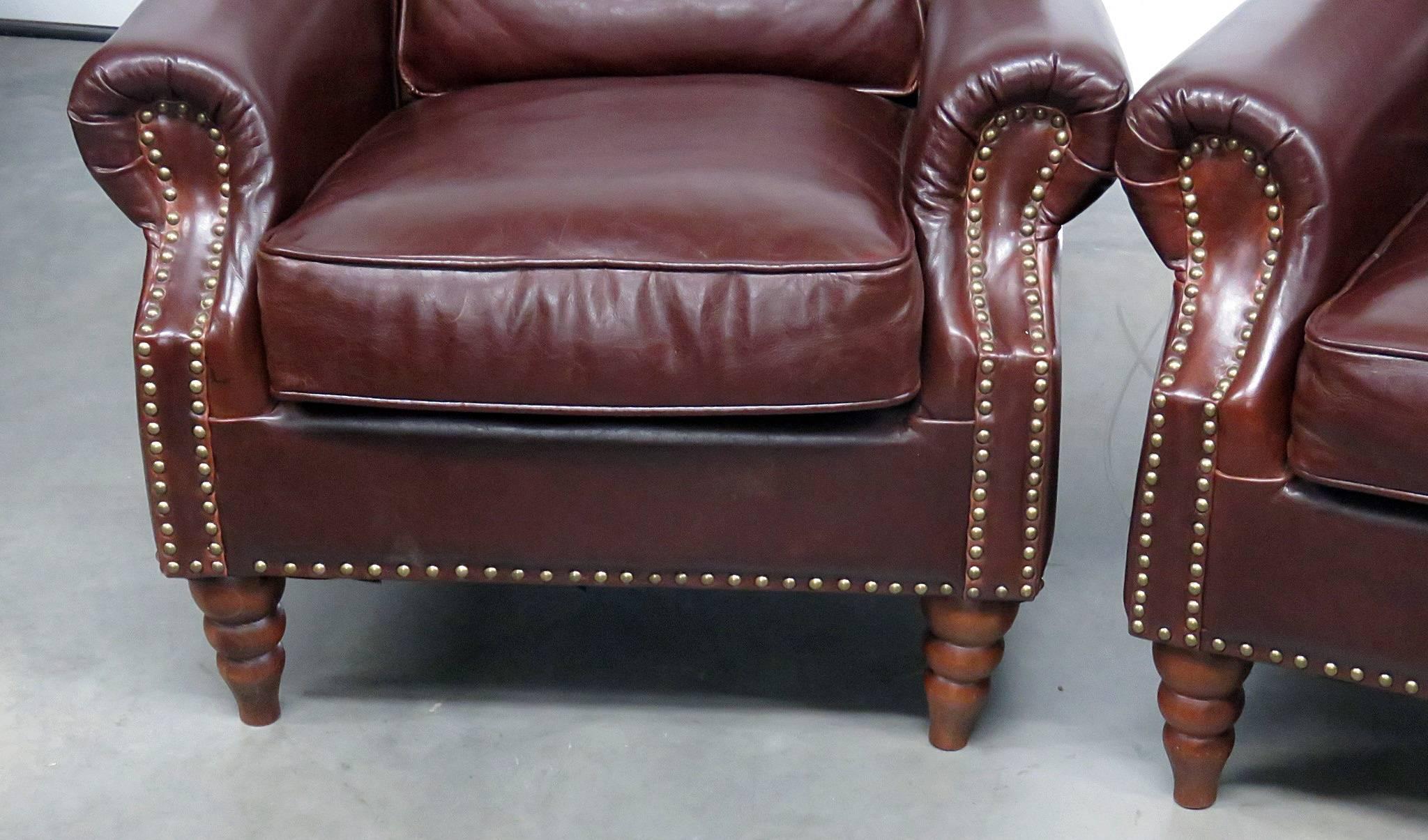 Pair of leather, brass studded club chairs.