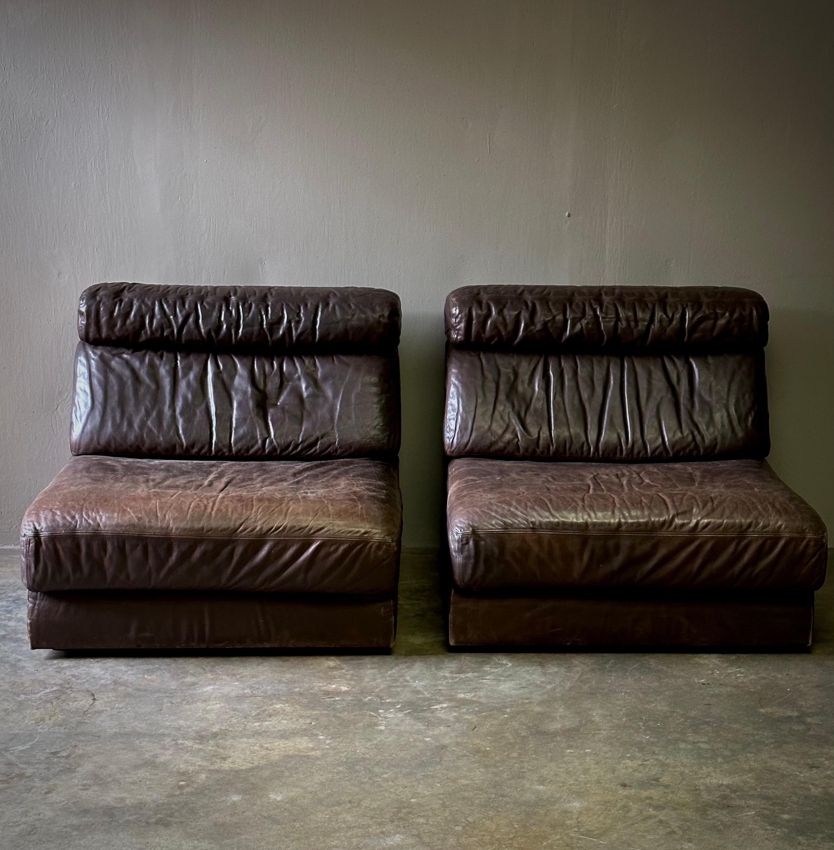 Pair of convertible 1960s De Sede lounge chairs in original chocolate brown leather. Chic, understated, and exceptionally comfortable, the pair unfolds to extend into reclining day-beds. Would work especially well in an office or guest space. The