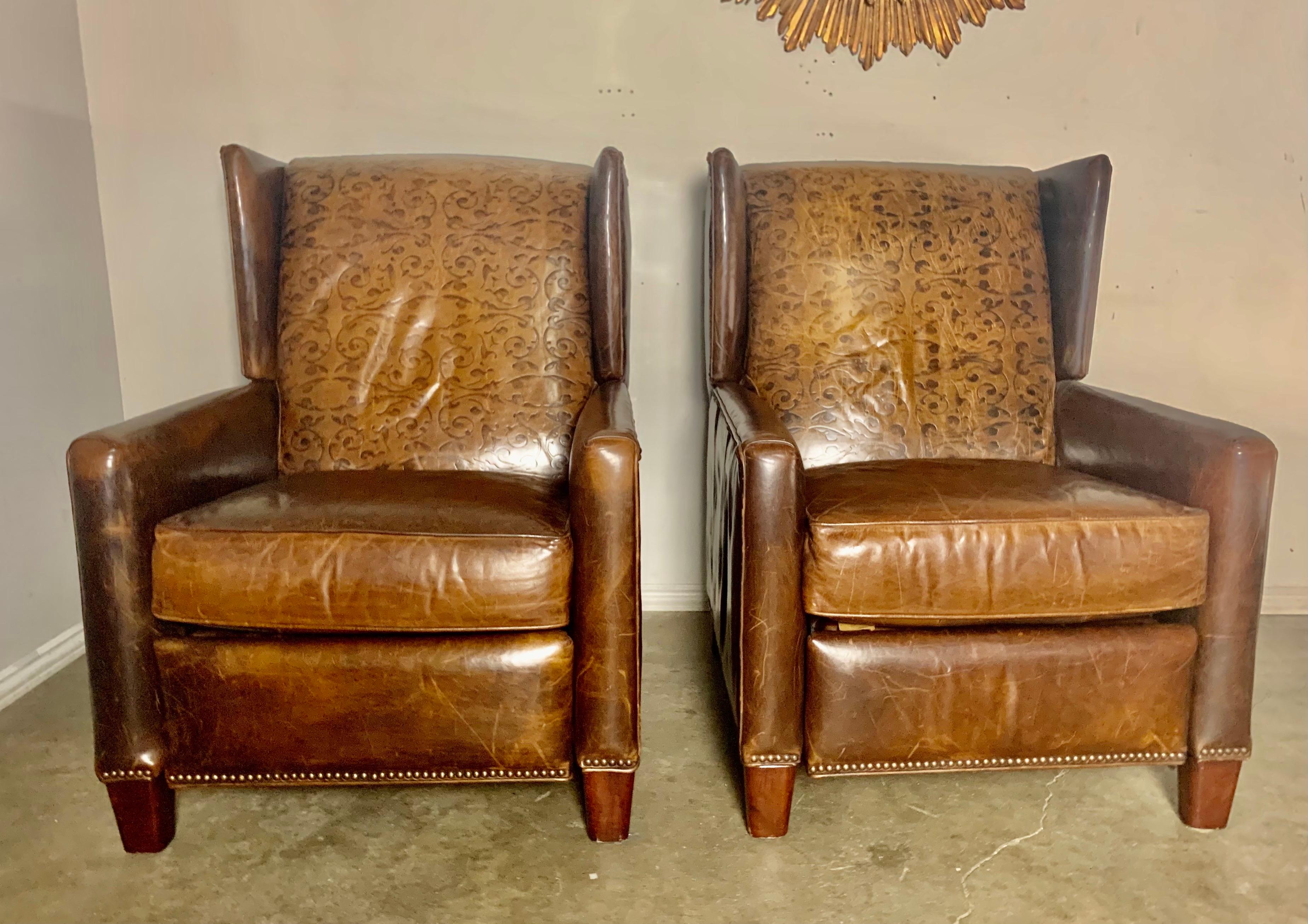 Pair of embossed leather armchairs / recliners. They are extremely comfortable and still work perfectly. There are marks on the leather but no tears or holes. Brass nailhead trim detail throughout.