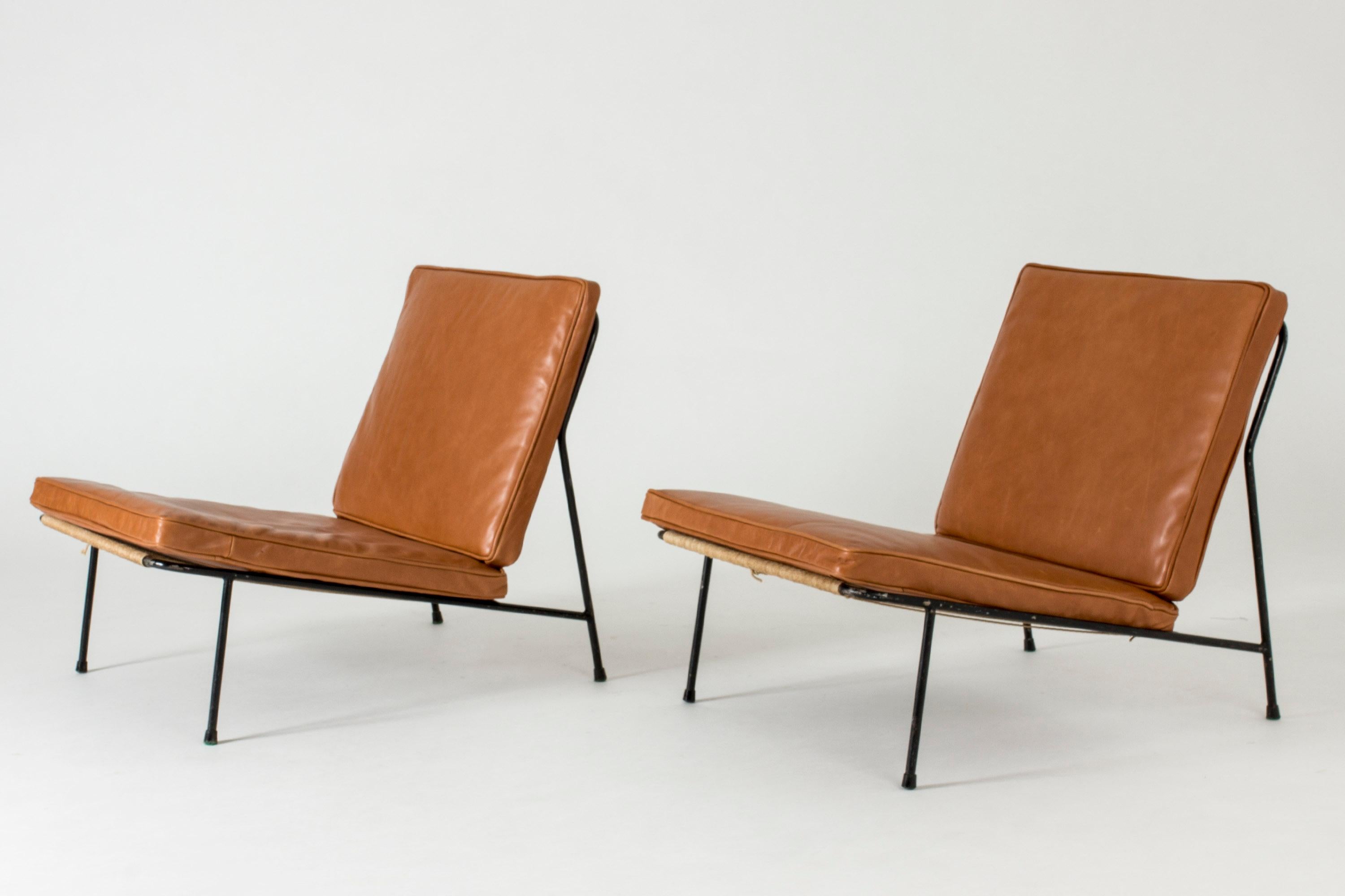 Pair of lounge chairs by Alf Svensson for Ljungs industries, later known as DUX, made in the 1950s. Black lacquered steel frames with removable cushions upholstered in luxurious cognac colored leather.

This model was first introduced at the