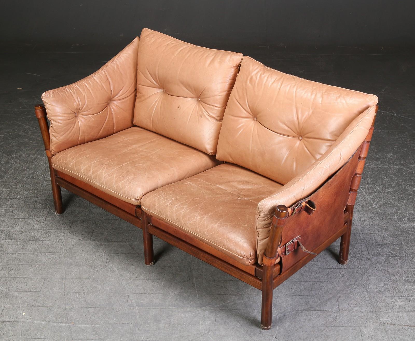 A pair of two-seat sofa, a popular design by well-known Swedish designer, Arne Norell (1917-1971) model `Illona, with stained beech frame, stretched with brown core leather, loose cushions upholstered in patinated leather. L. 150 cm. Traces of wear