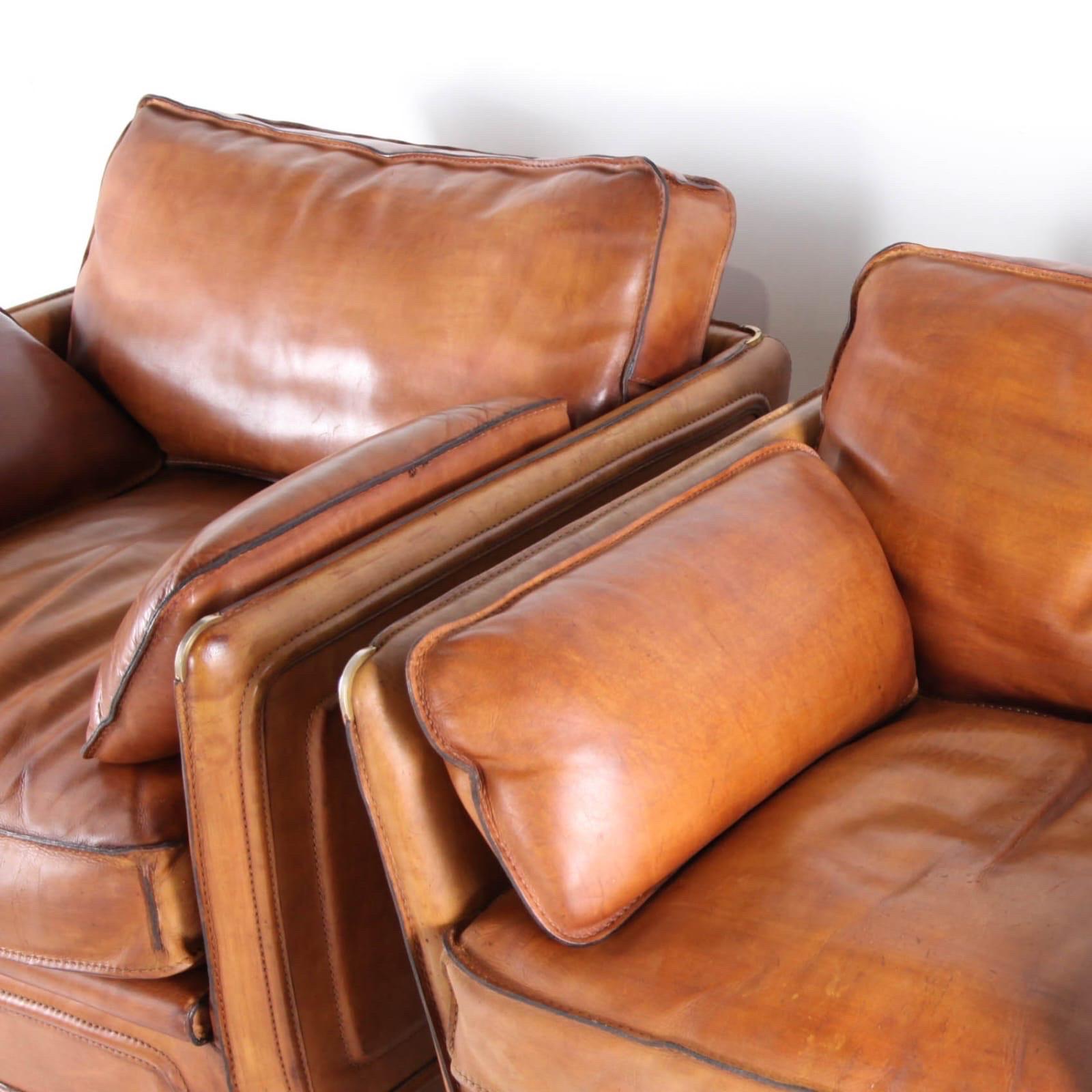 Rare pair of 1970’s buffalo thick leather Roche Bobois armchairs. 
Brass accents, wooden legs, goose feathers, saddle stitches, clip-on cushions…
Great quality, patina and condition. And very comfy..