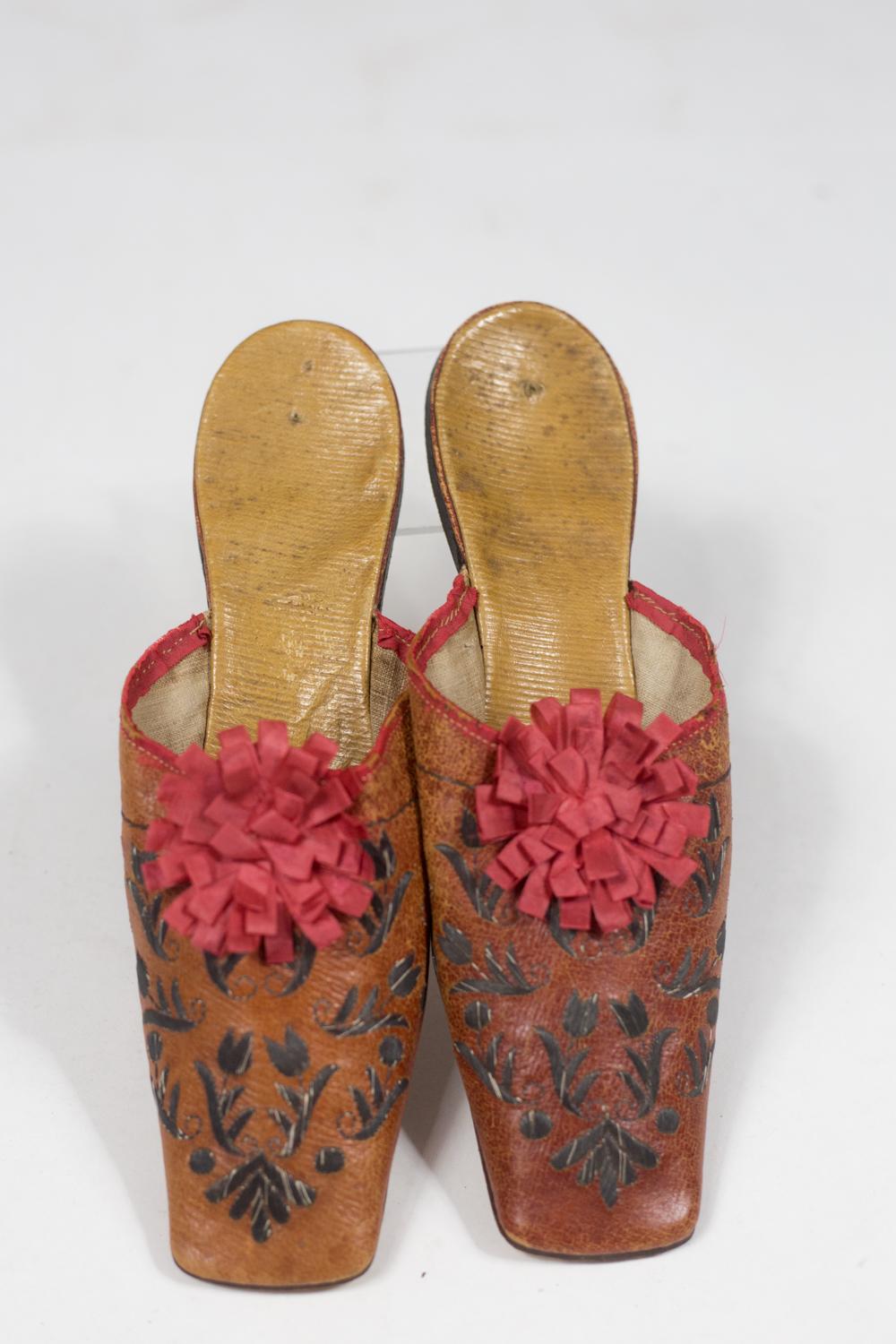 Circa 1790/1820
France
 
Belle paire de mules orientalistes de collection datant du début du XIXe siècle. Tige à bout carré en cuir fauve brodé de tulipes en lame de métal argenté et cassettes en ruban de soie cerise. Poignets en ruban de soie rouge