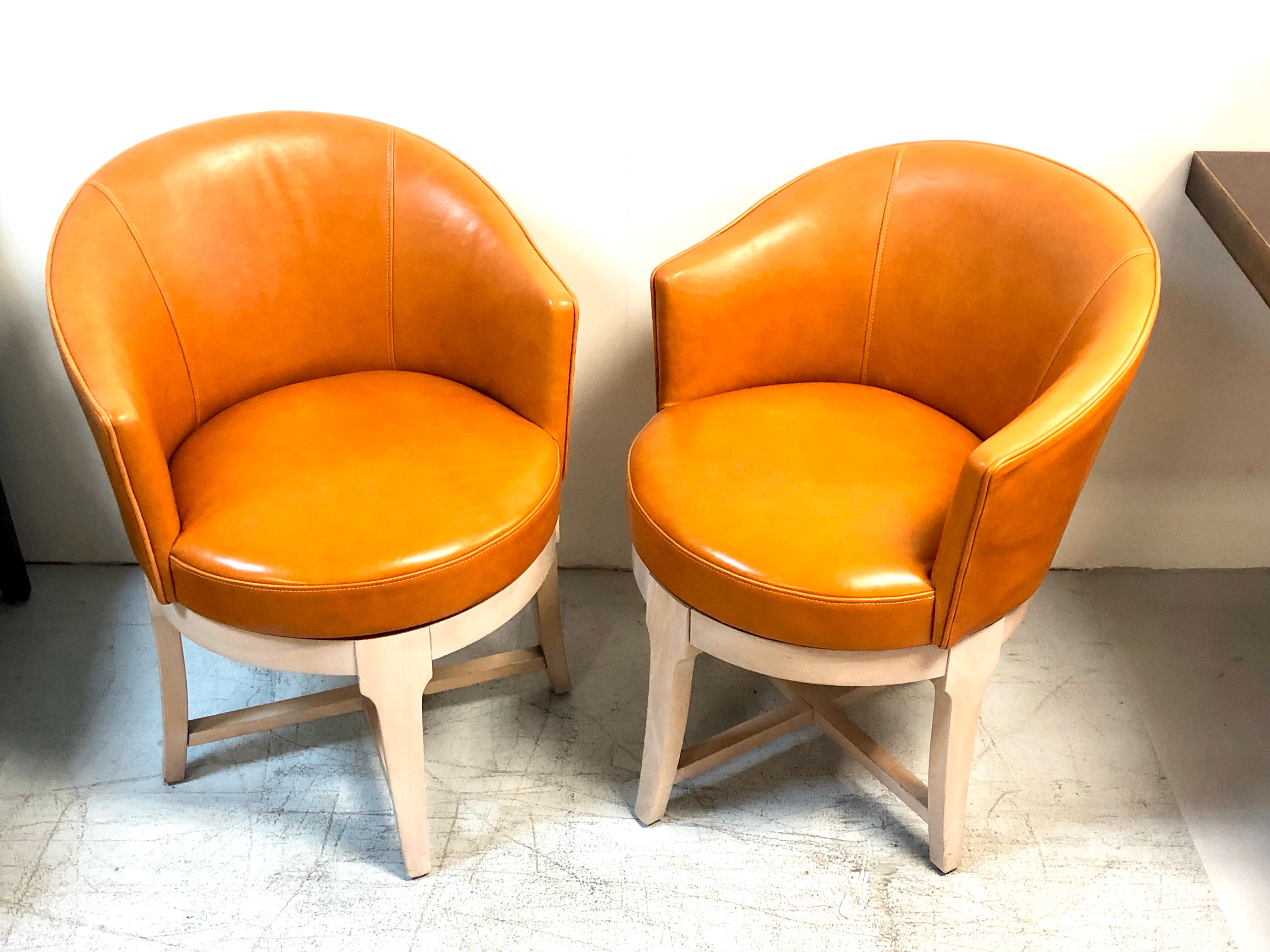A pair of chic swivel chairs. Cognac leather upholstery on a round solid wood base.