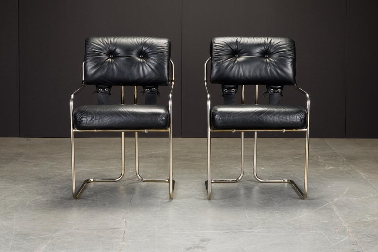 Currently, the most coveted dining chairs by interior designers are 'Tucroma' chairs by Guido Faleschini for i4 Mariani, and we have this incredible pair of Tucroma armchairs in beautiful black leather with brass tone steel frames. 

The seats and