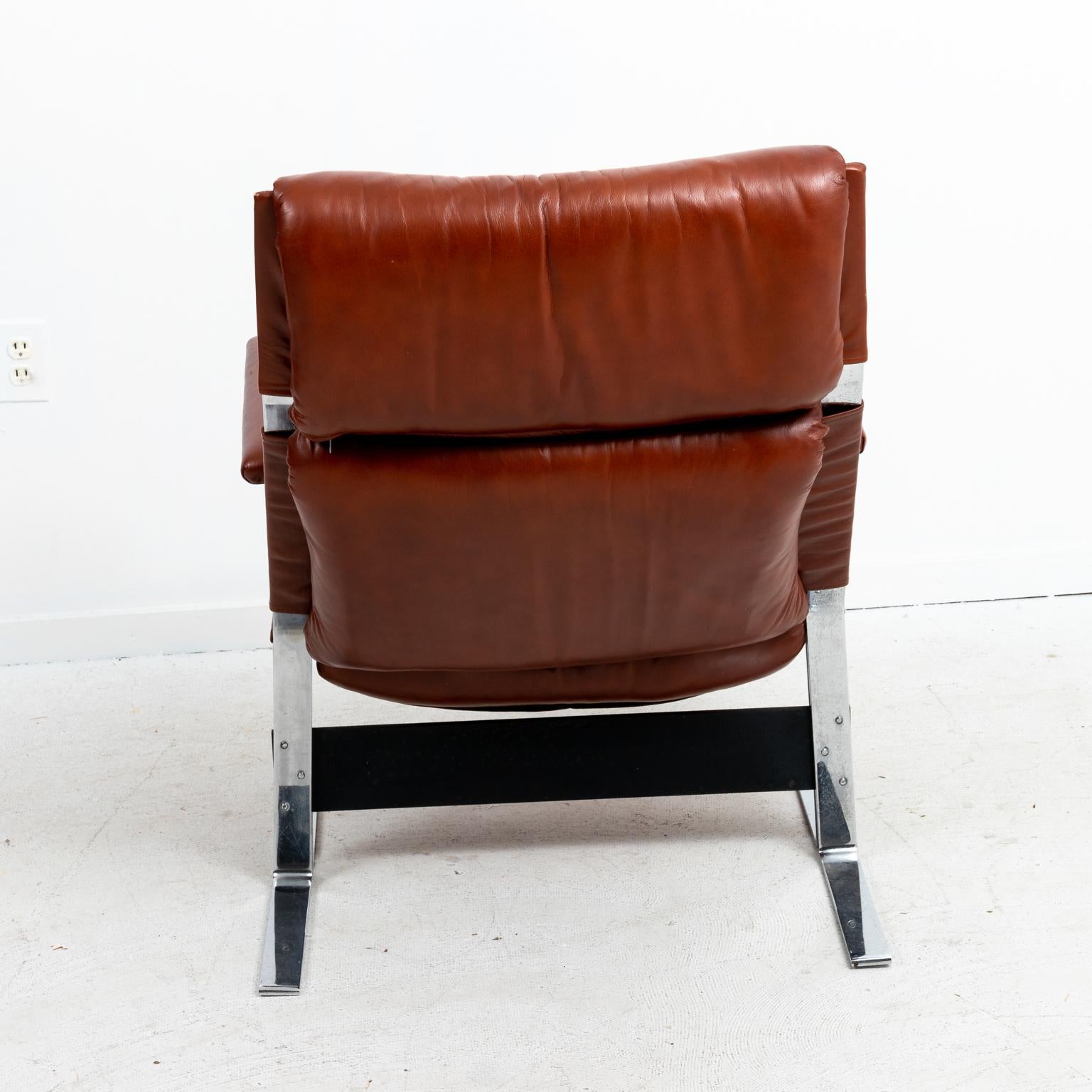 Mid-Century Modern style leather upholstered chairs with matching ottomans and polished metal frame. Please note of wear consistent with age as seen on the leather along with patina to the metal. The ottomans measure 26.00 Inches wide by 20.00