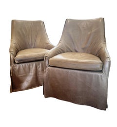 Pair of taupe leather, skirted slip-covered Verellen chairs on casters