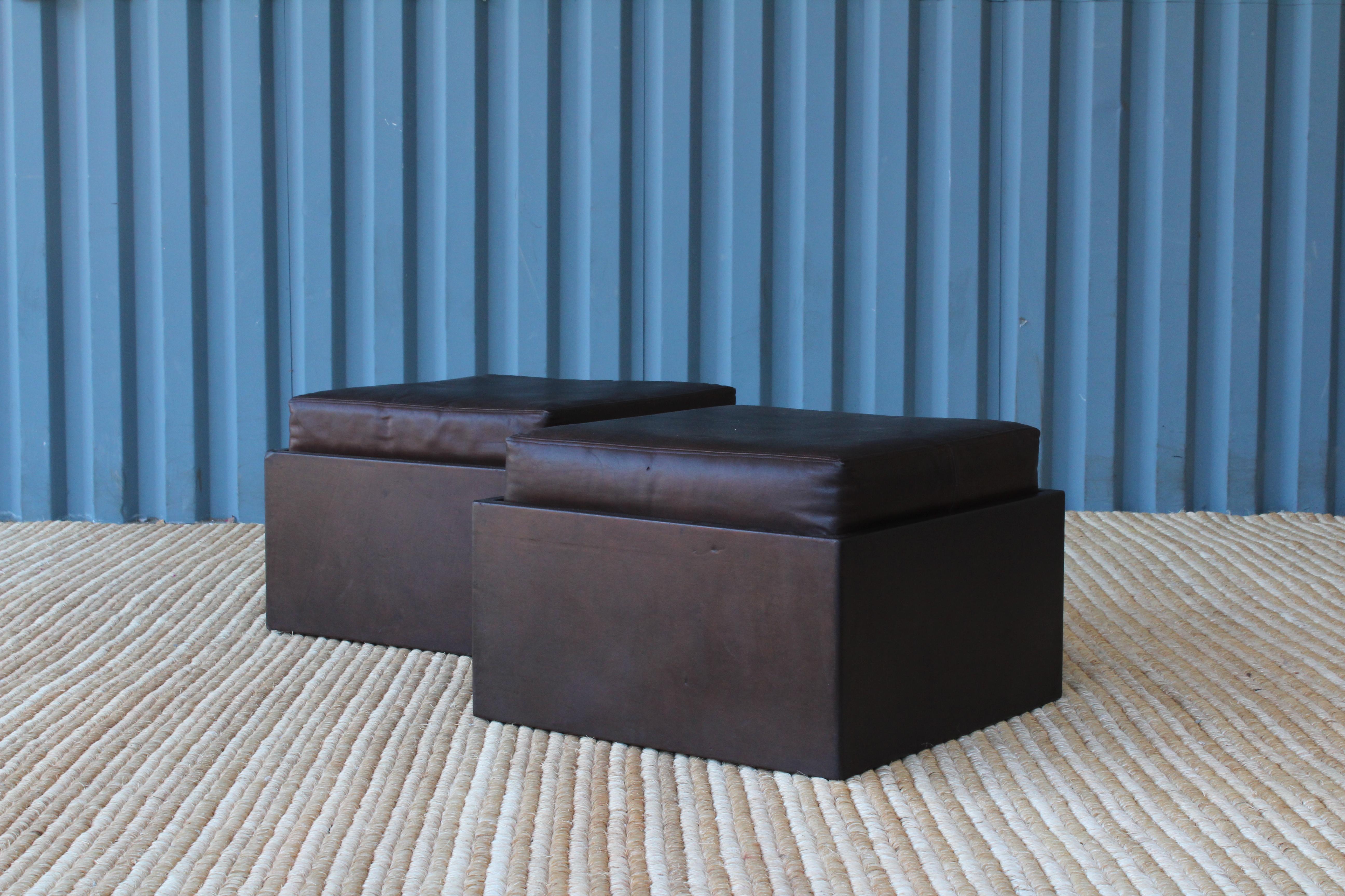 Pair of 1970s leather wrapped ottomans on rolling casters with removable cushions.