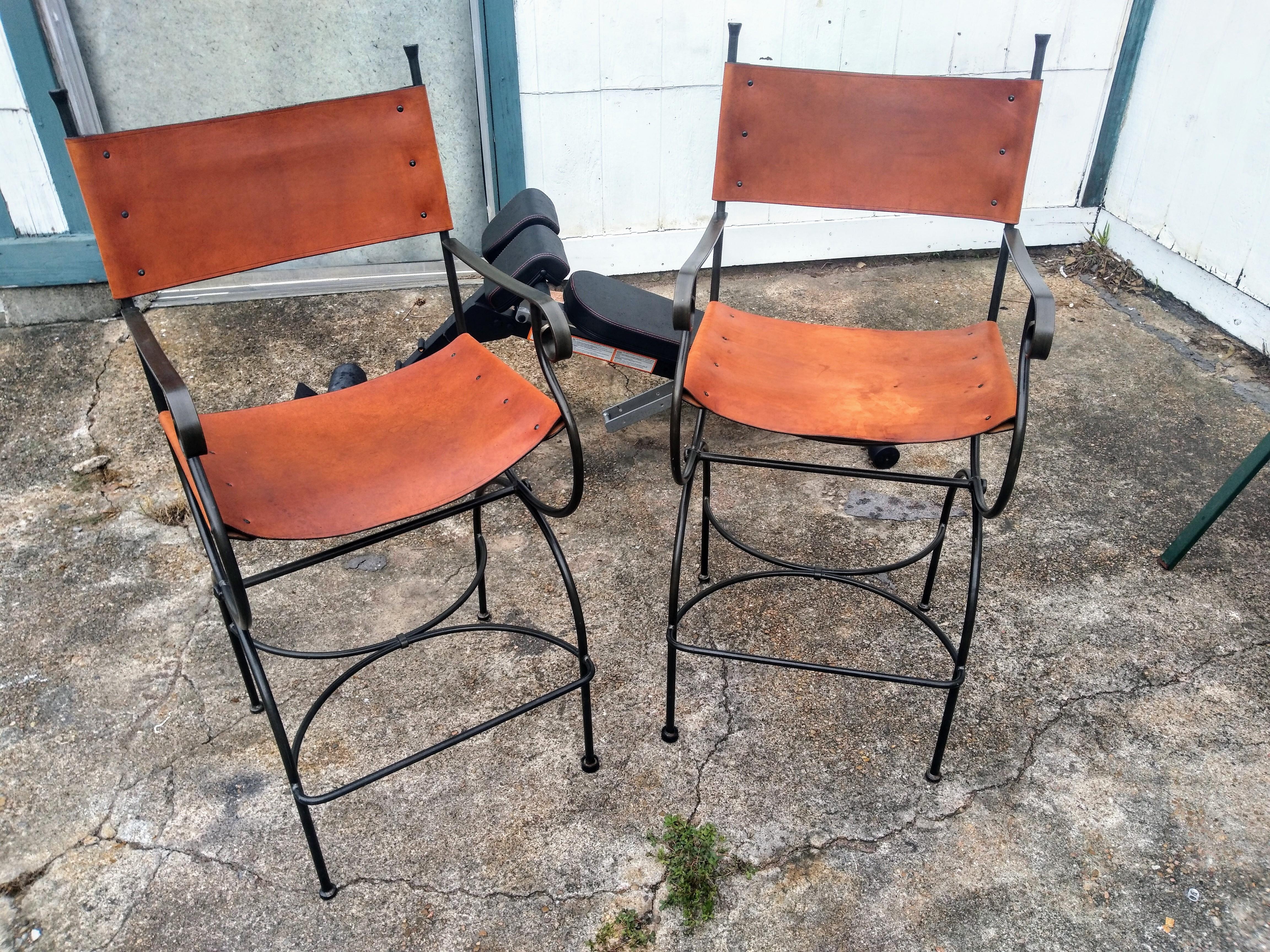 Pair of Legacy Barstools by Charleston Forge 

A pair of Charleston Forge wrought iron and leather barstools. Forged heavy black wrought iron with caramel leather seats and backs. 
Accented with tapered finials to the posts of the seat backs and