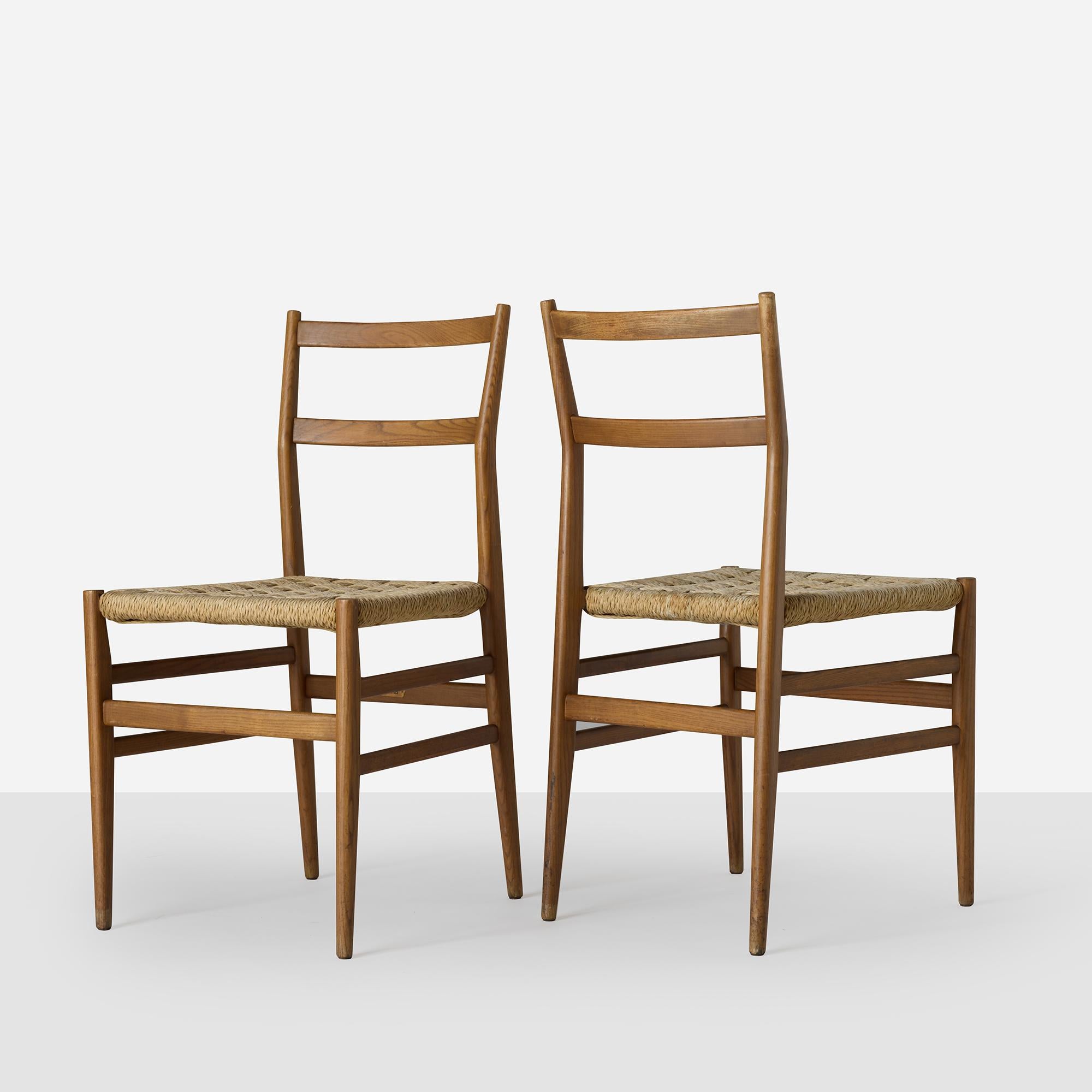A pair of dining chairs by Gio Ponti in ash with rush seats woven in a basket weave pattern, all retaining their original label.

Priced for the pair.