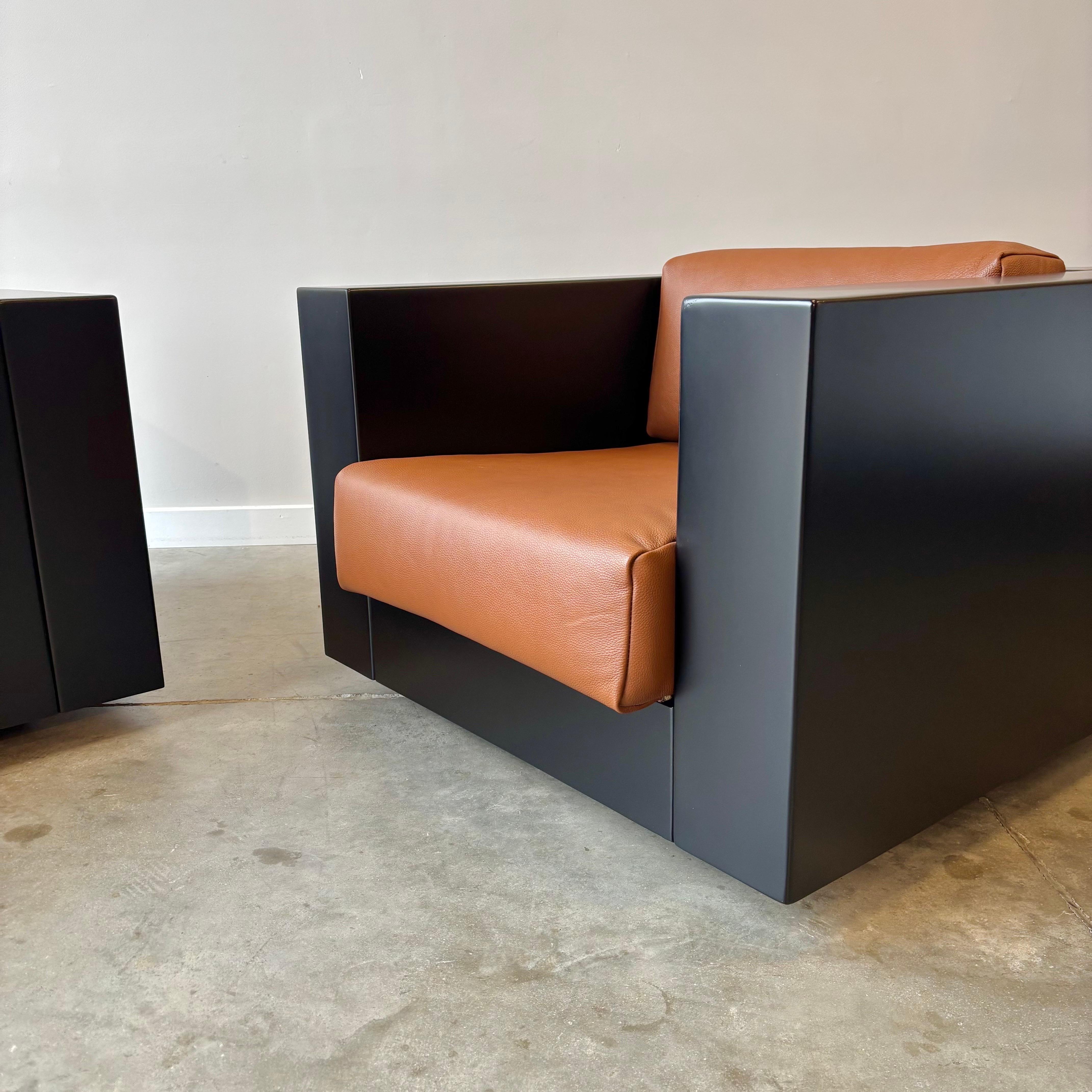 
Paire de chaises Saratoga conçues par Lella et Massimo Vignelli pour Poltronova, présentant la structure enveloppante caractéristique du design. Les caisses en contreplaqué créent des coques continues qui entourent la zone d'assise, les accoudoirs