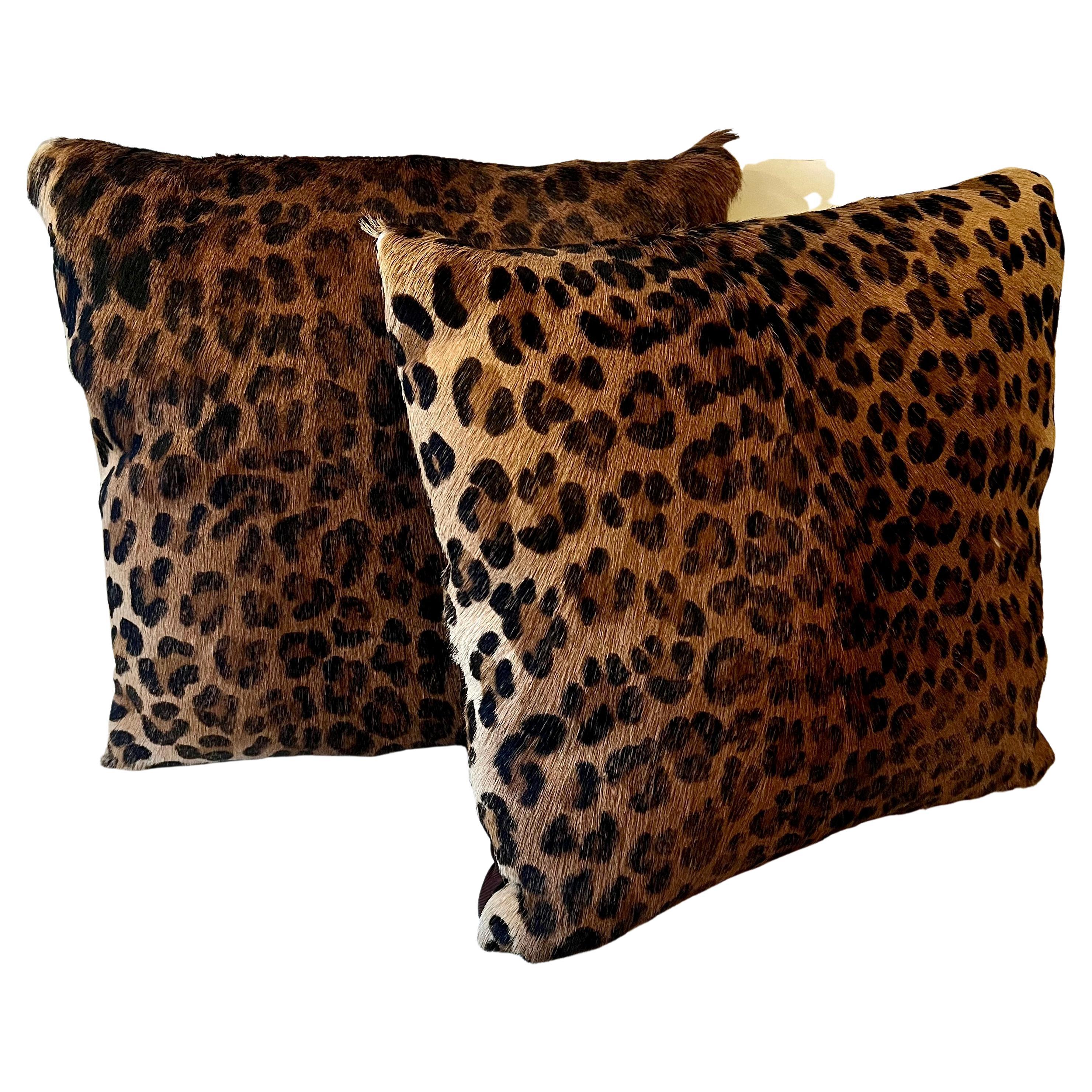 A pair of leopard cowhide printed pillows with a satin back and zipper. The pair are very nice and work well in many spaces. a compliment to ethnic or Ralph Lauren style rooms, but work most anywhere.
