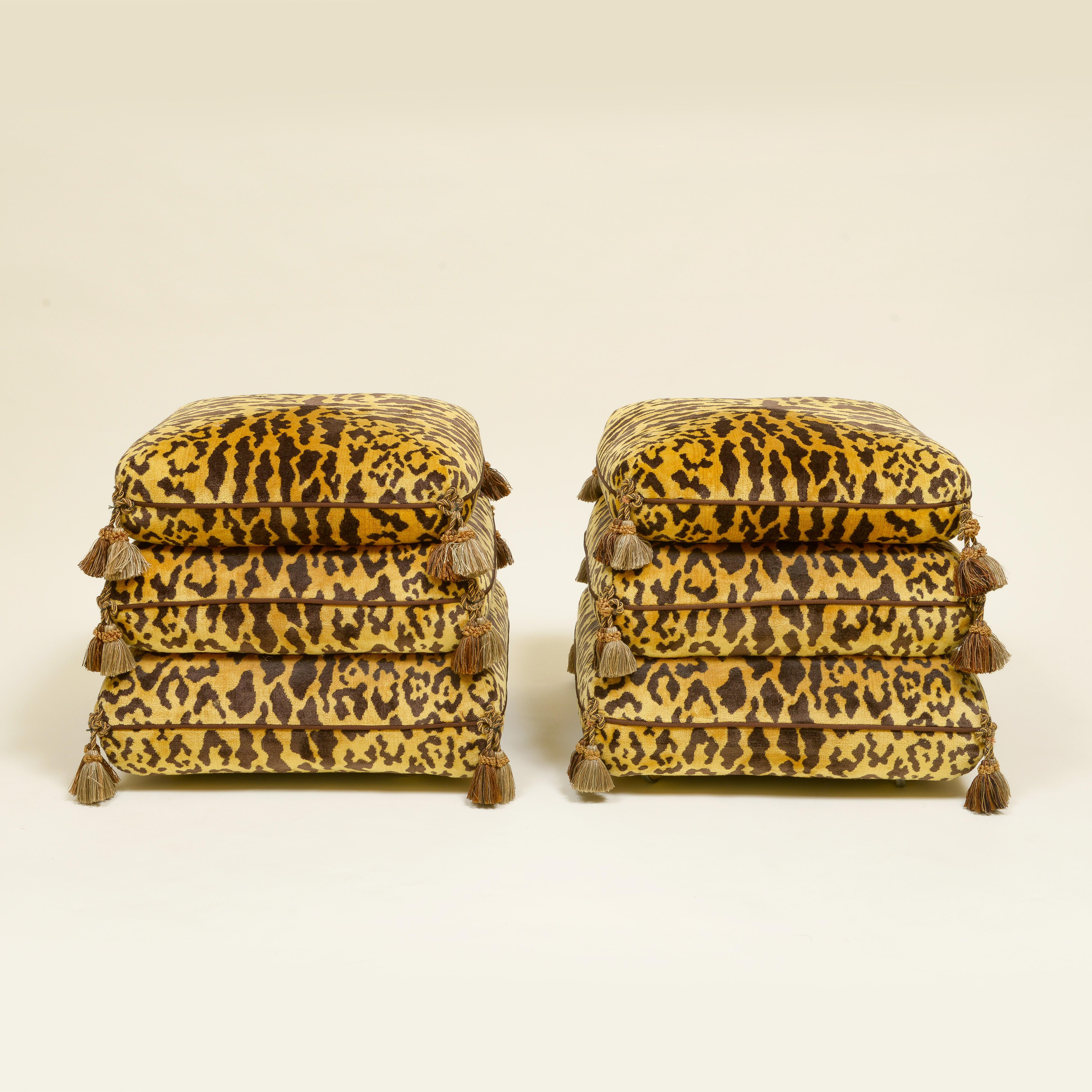 Each ottoman in the form of three graduated Turkish cushions, trimmed with cord and tassels, on casters.