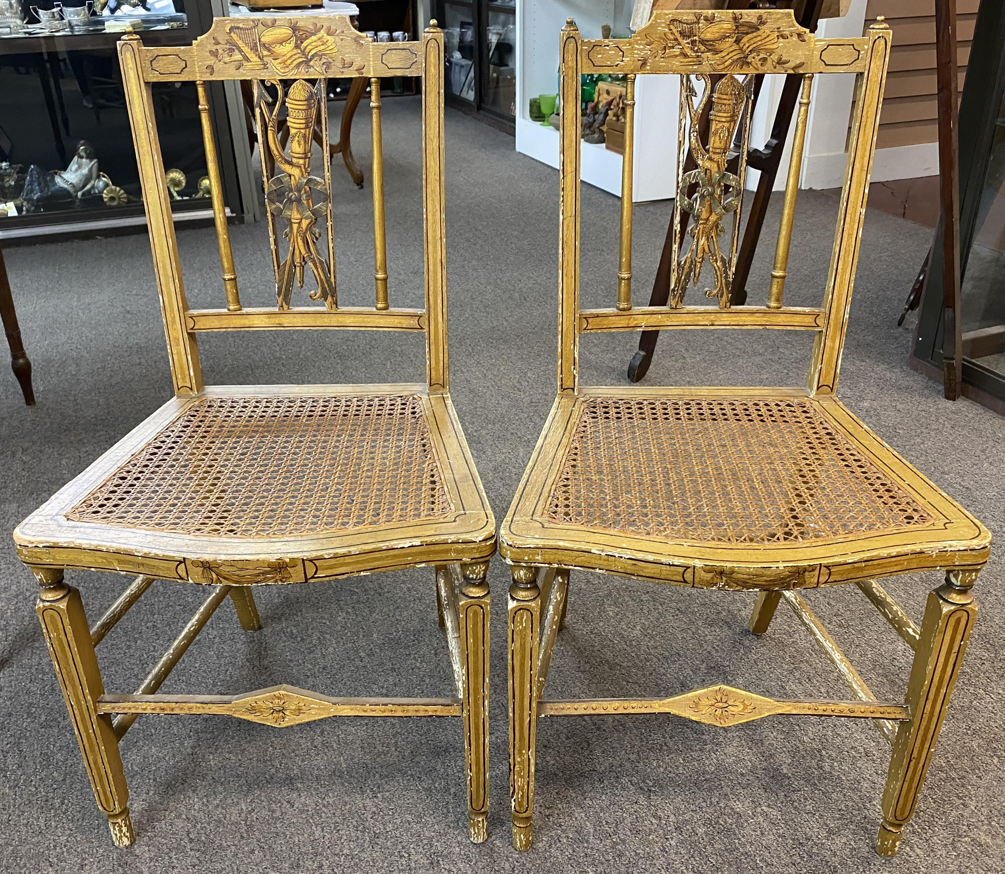 A nice pair of hand painted golden yellow cane seat fancy chairs, branded “L. Barnes” on the underside, circa 1820. Paint decorated in a musical motif crest , the shaped back splat featuring a torch, ribbon, bows & arrow, with a swag decorated seat