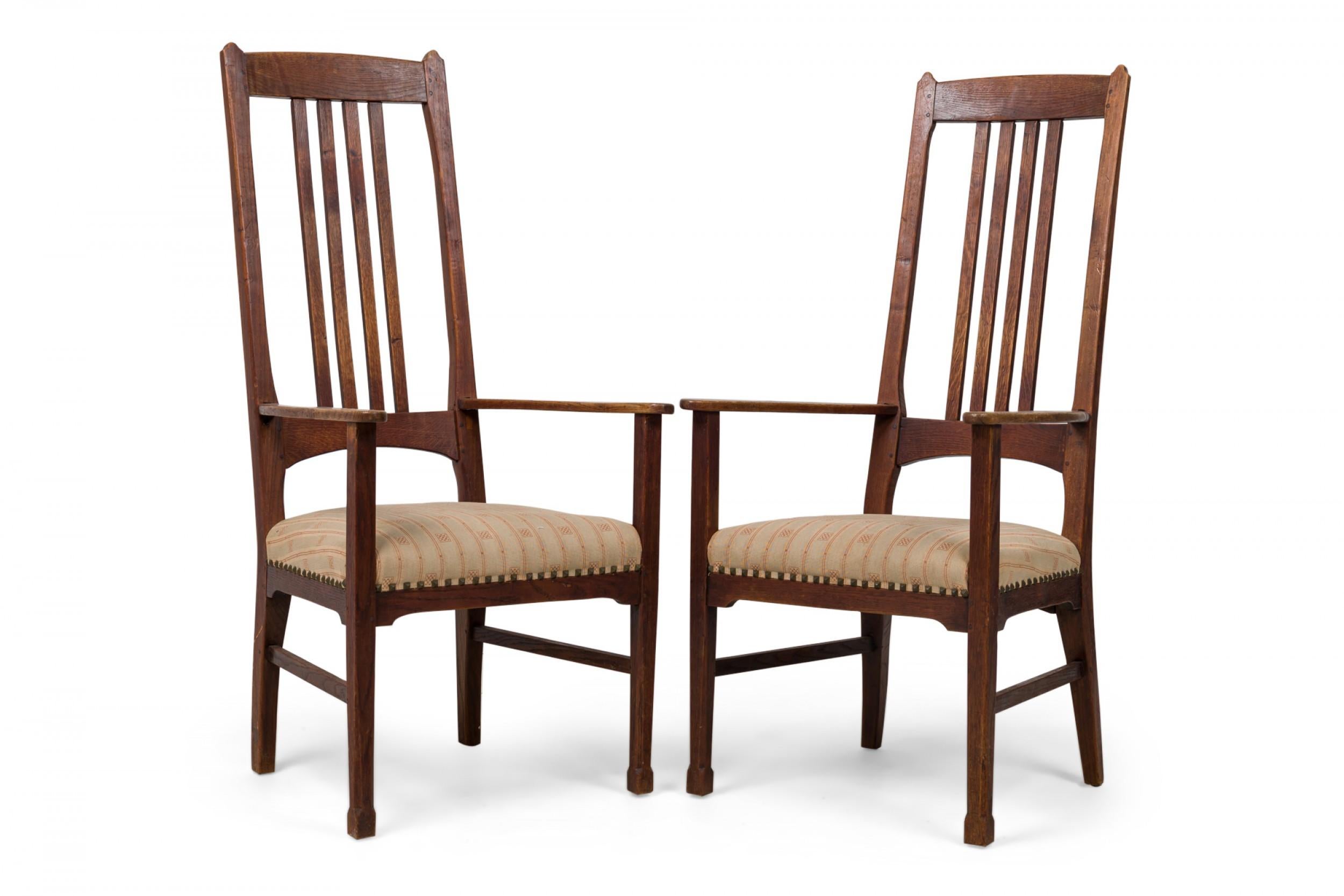 PAIR of English Arts and Crafts high back armchairs with shaped backrest, evenly spaced centered vertical slat supports, flattened arms, beige upholstered seat in a checkerboard striped pattern, square brass nailhead trim, shaped cut out apron and