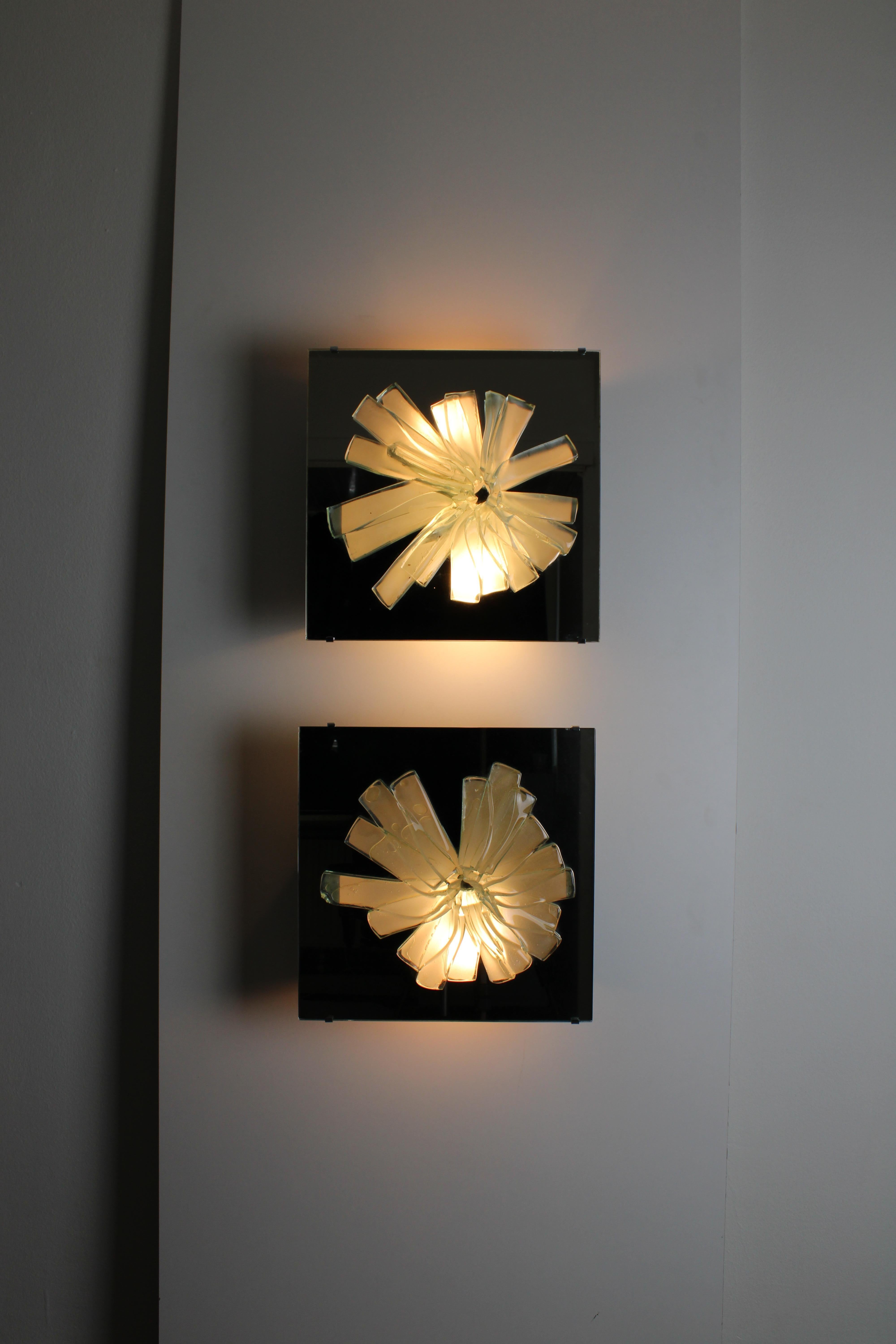 Set of 2 very rare Lichreliëf wall lamps by RAAK Amsterdam. The glass shards are handmade and melted together.
Behind the glass are 2 sockets that shine through the multiple fractured glass relief. The glass light fracture is surrounded by mirrored