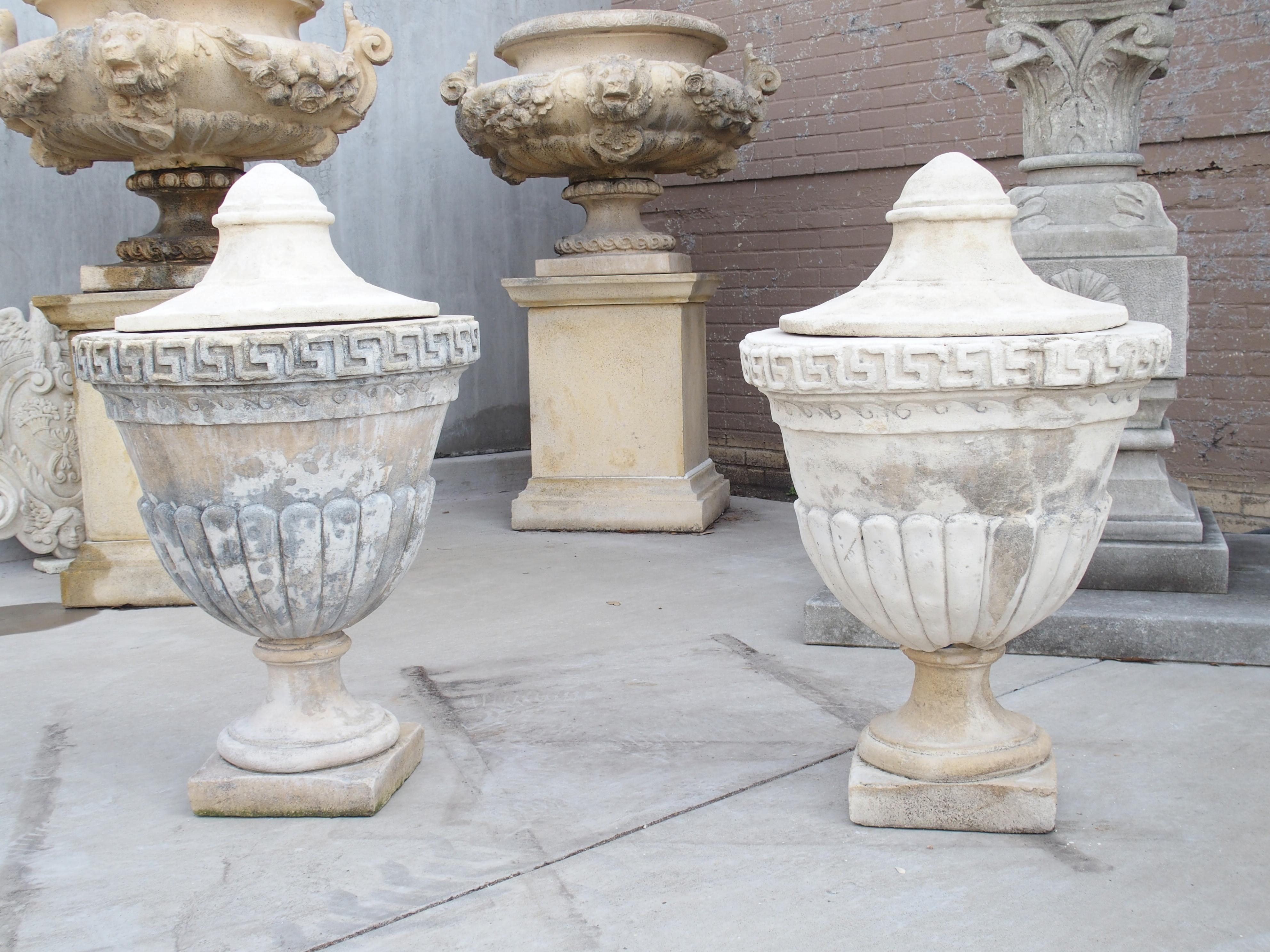 Hand-cast by truly skilled Southern Italian artisans, this pair of lidded limestone urns are in the Neoclassical style. Each urn is a testament to the artistry of hand casting, eschewing molds for a truly unique character. Topped with conical lids,