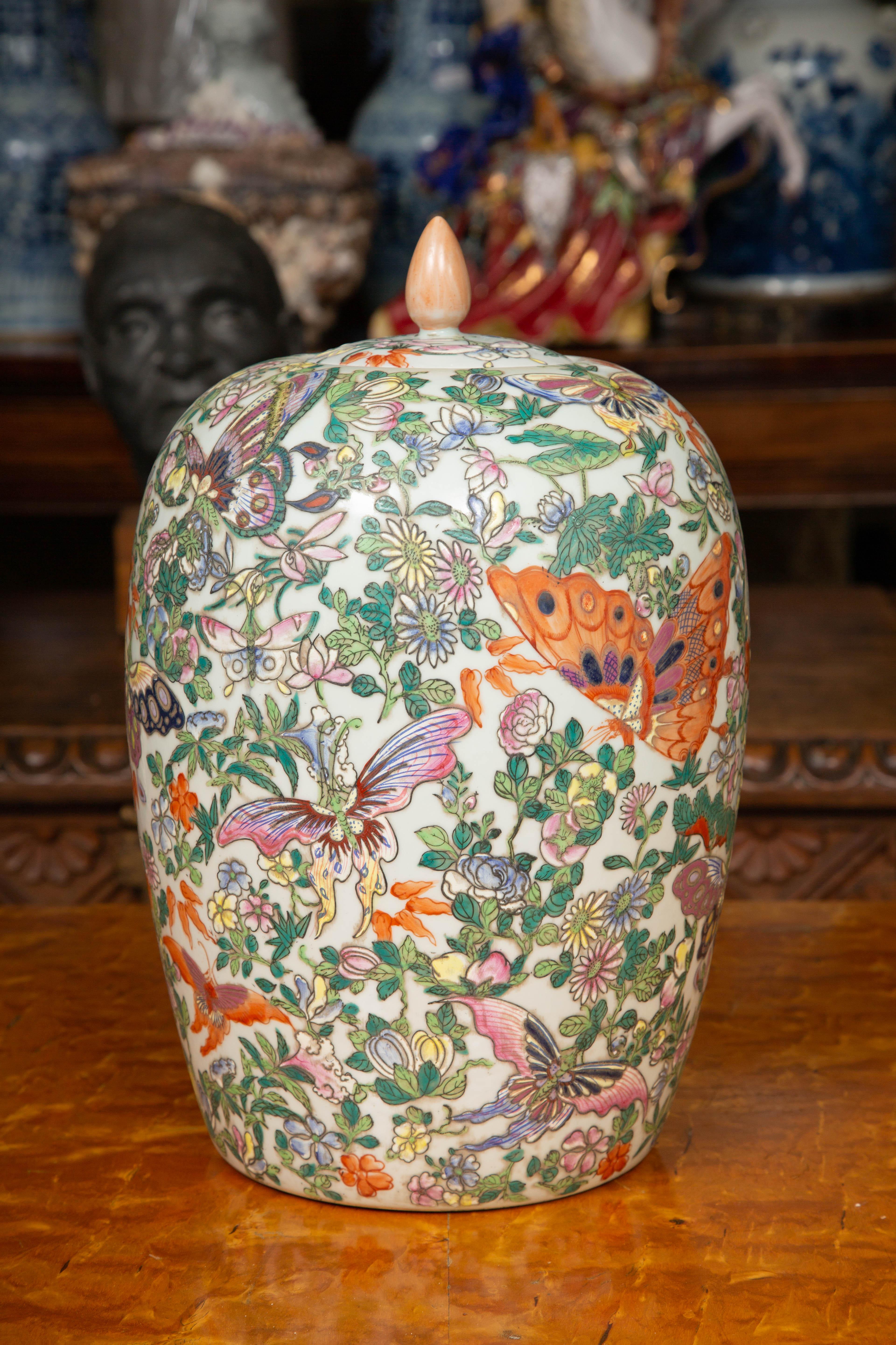These are a colorful and detailed pair of Chinese Canton export butterfly pattern lidded melon shaped Asian jars. The hand painted jars yield a relief from the exquisitely overglazed enamel design, 20th century.