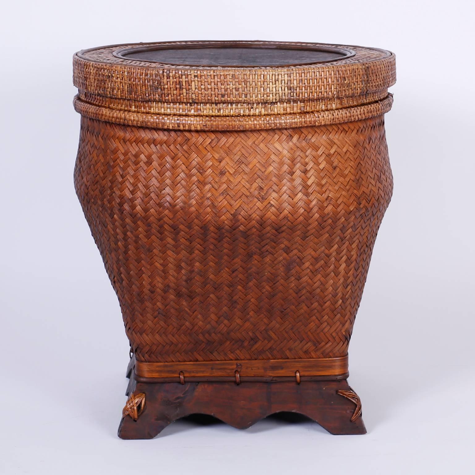 Dynamic pair of vintage lidded rattan baskets that can be utilized as end tables or nightstands. Crafted with intricately woven reed having removable lids, Bombay form and carved hardwood bases.