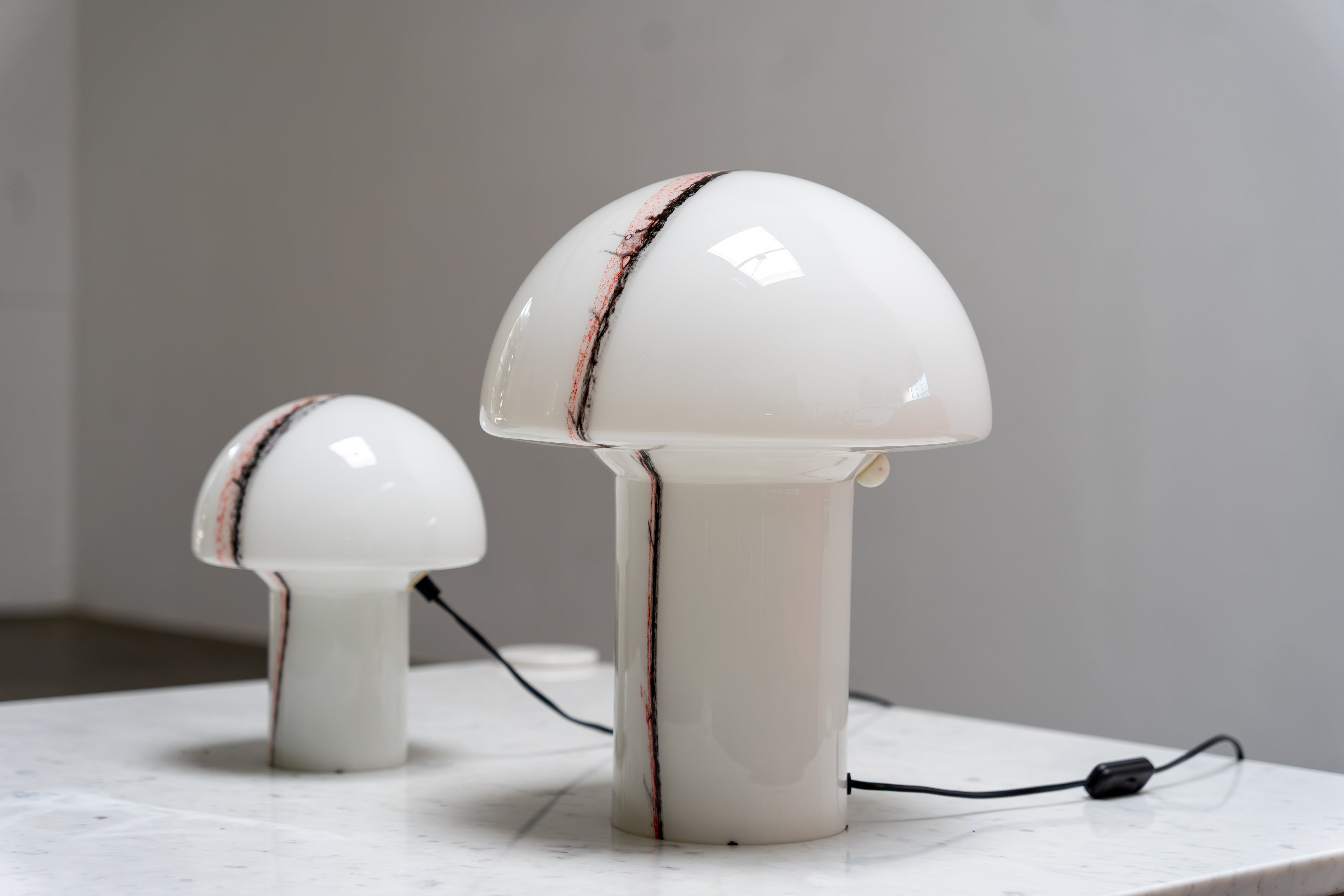 Paire de lampes de table en forme de champignon par Peill & Putzler, Allemagne, années 1970.
Chaque lampe est fabriquée à partir d'une seule pièce de verre soufflé et moulé, avec des inclusions de pigments rouges et noirs appliqués de manière